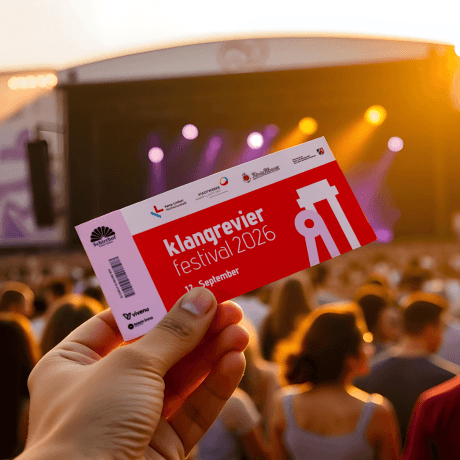 Eine Hand hält ein KlangRevier-Festival-Ticket in die Luft. Im Hintergrund sind eine Bühne mit Scheinwerfern und eine feiernde Menschenmenge zu sehen. (Bild ist KI-generiert.)