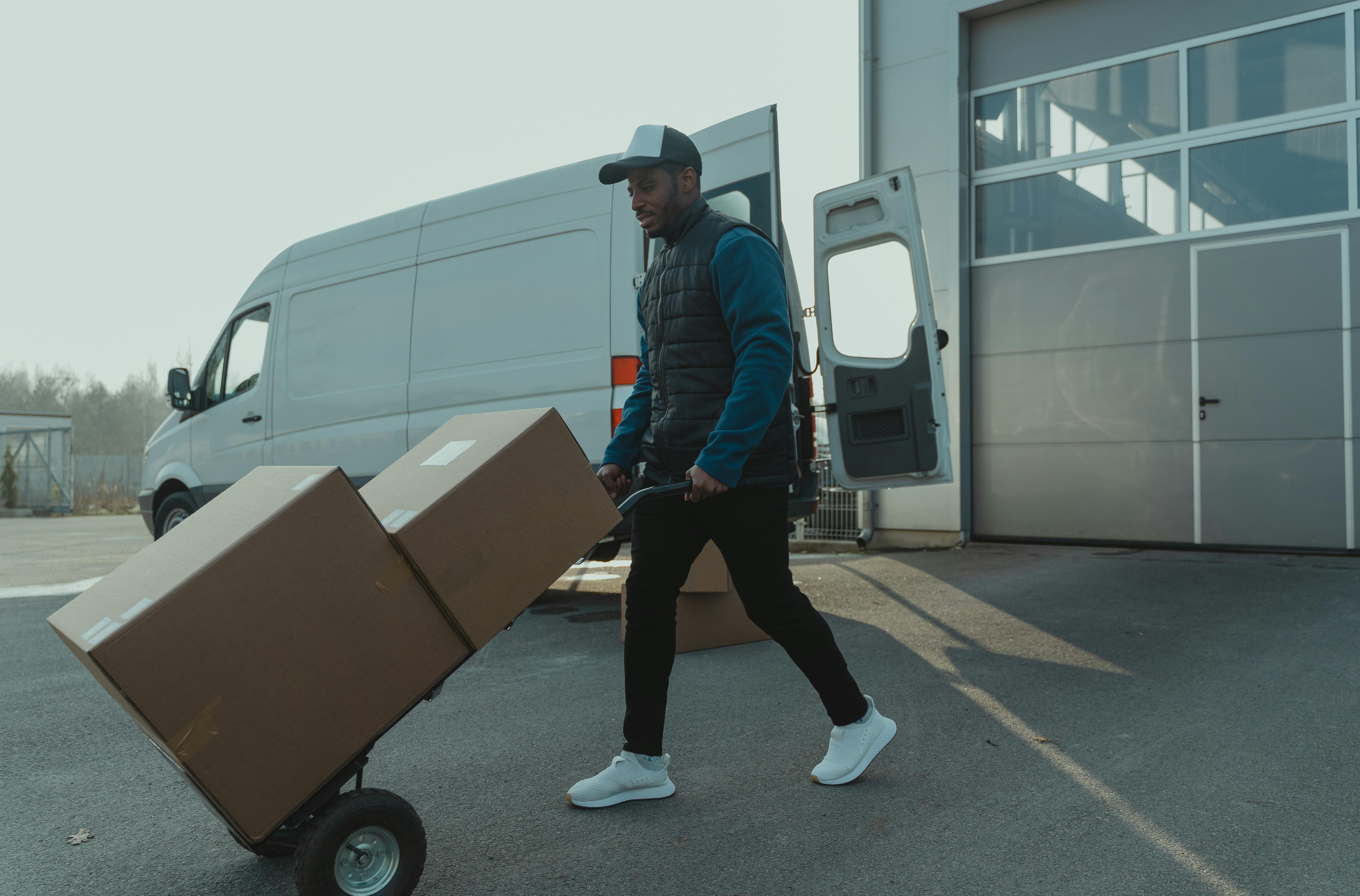 Delivery worker transporting packages on a hand truck outside a warehouse