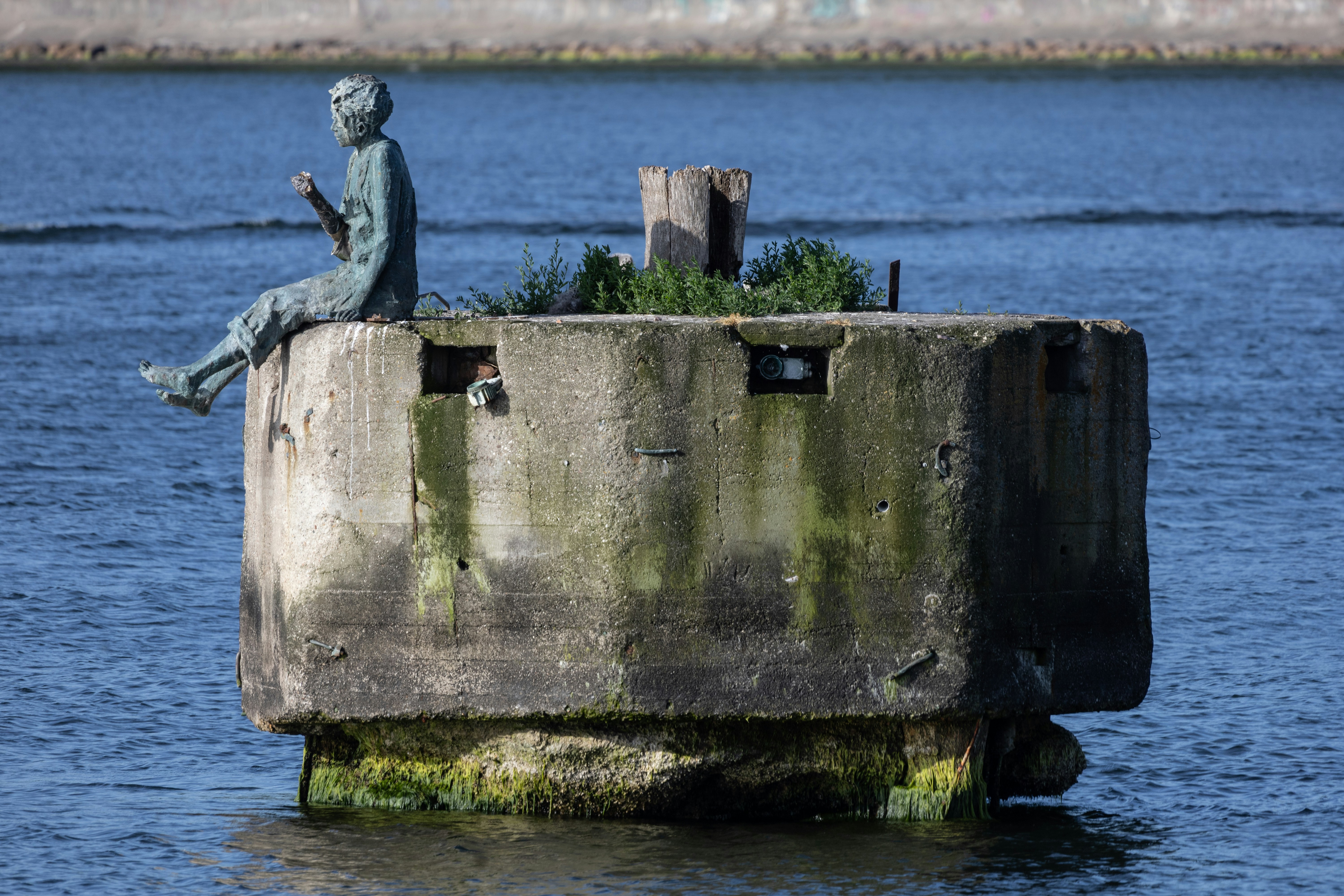 A statue of a man sitting on top of a cement block