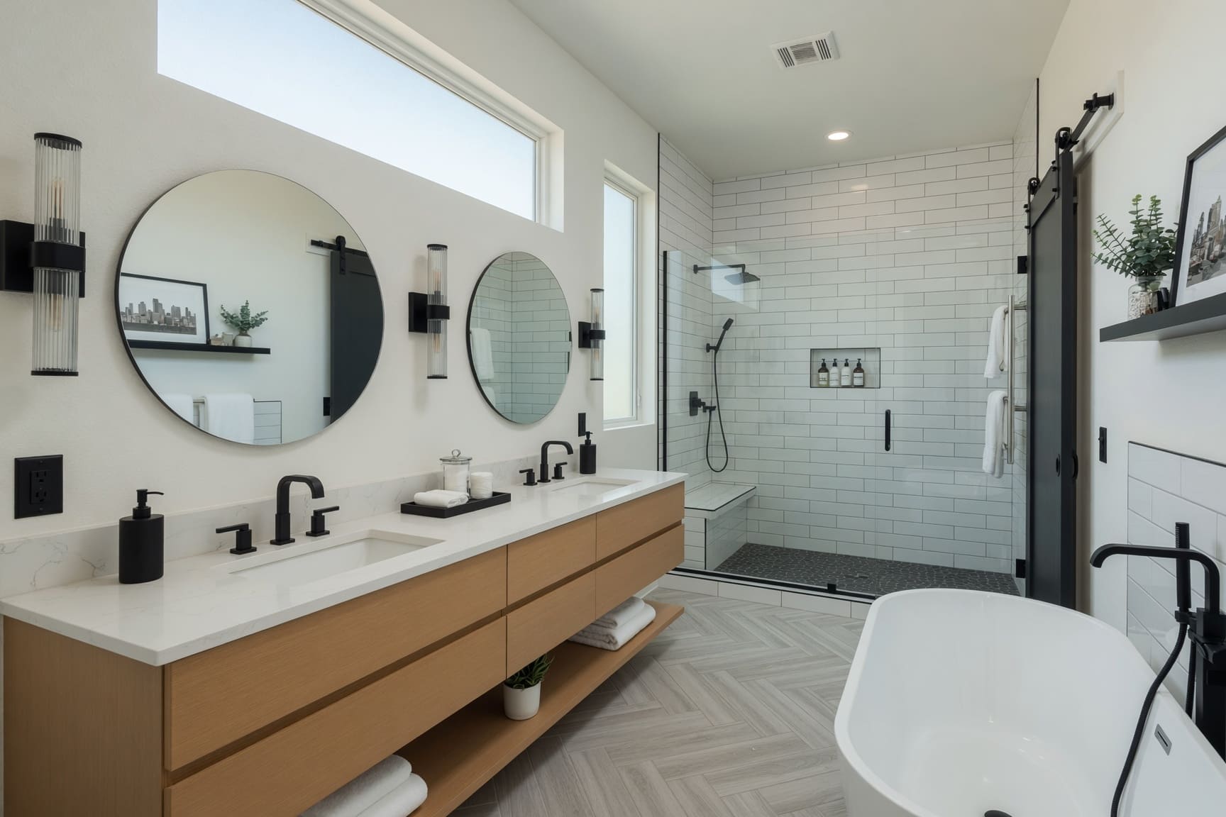 Bathroom with double vanity, round mirrors, and walk-in shower
