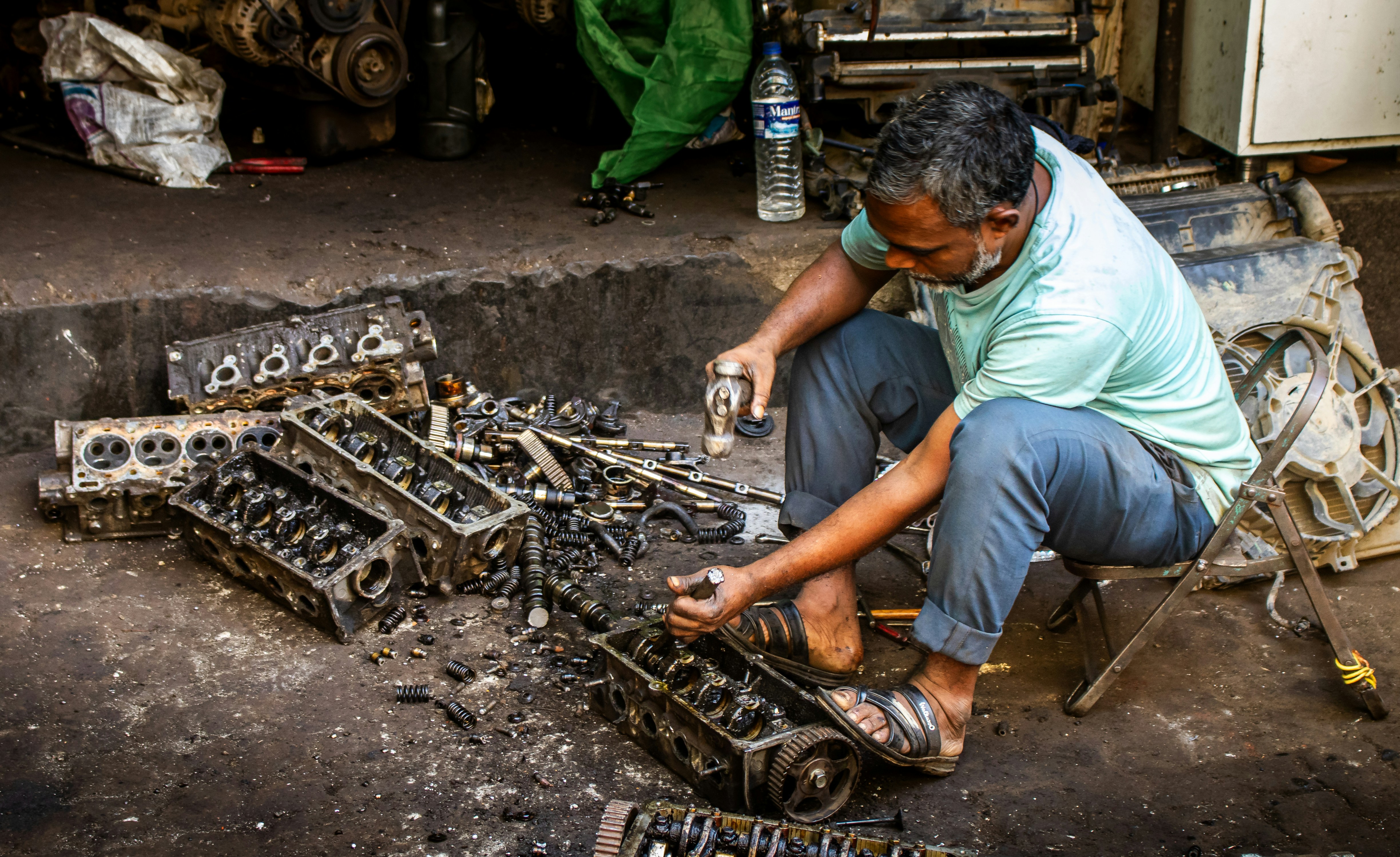 Mechanic working on car engine parts in workshop.