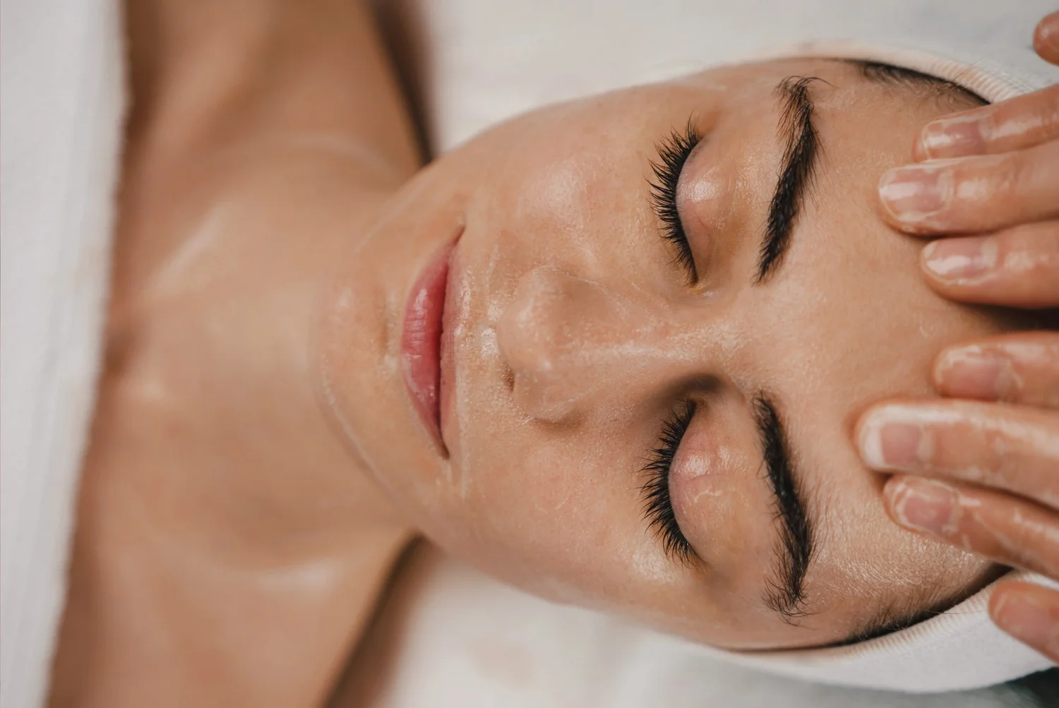 Woman lying back with eyes closed while a provider gently touches her forehead