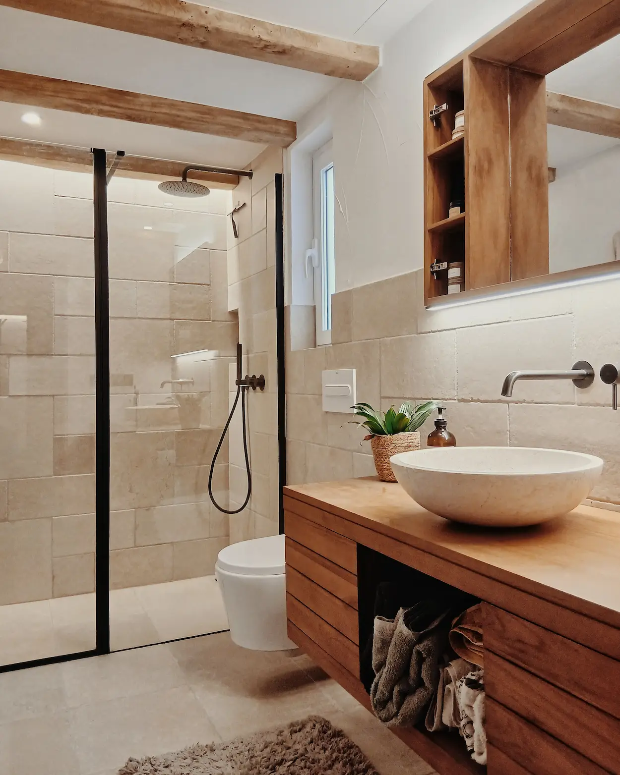Gut beleuchtetes Badezimmer mit Holzbalkendecke und begehbarer Dusche im Referenzprojekt Casa Terra mit individuellem Interior Design.