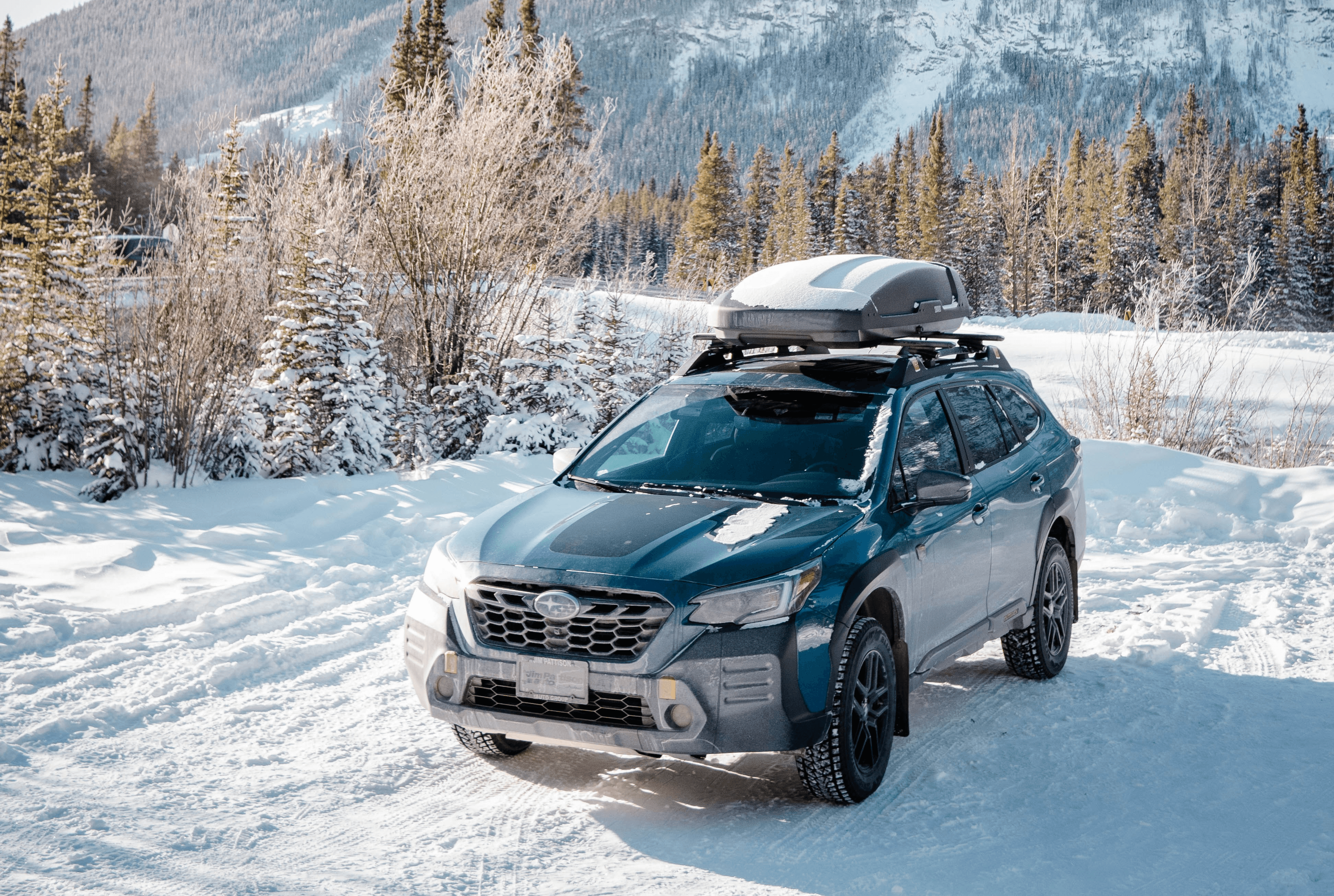 a car parked in the snow in front of a mountain