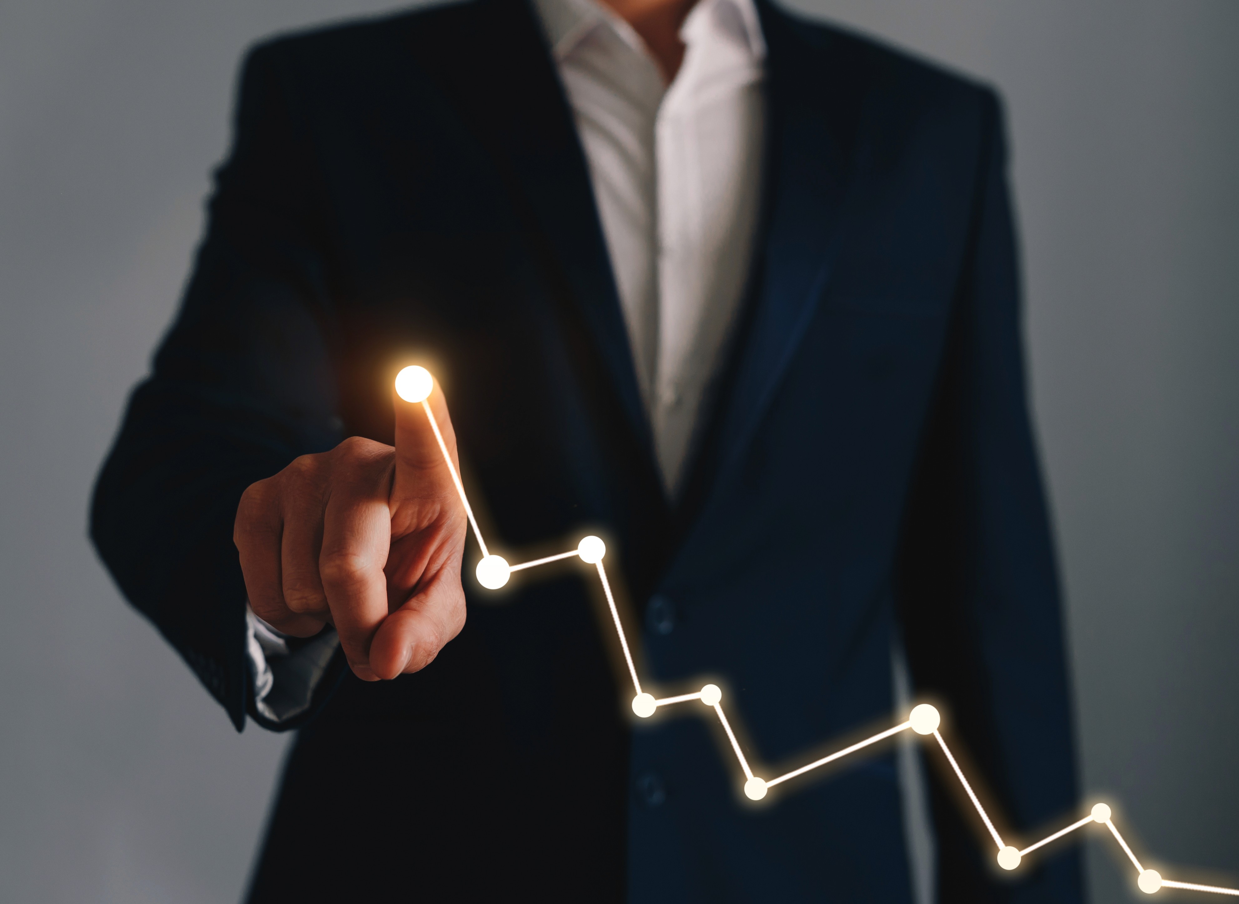 Businessman pointing at upward glowing line graph representing company growth and success