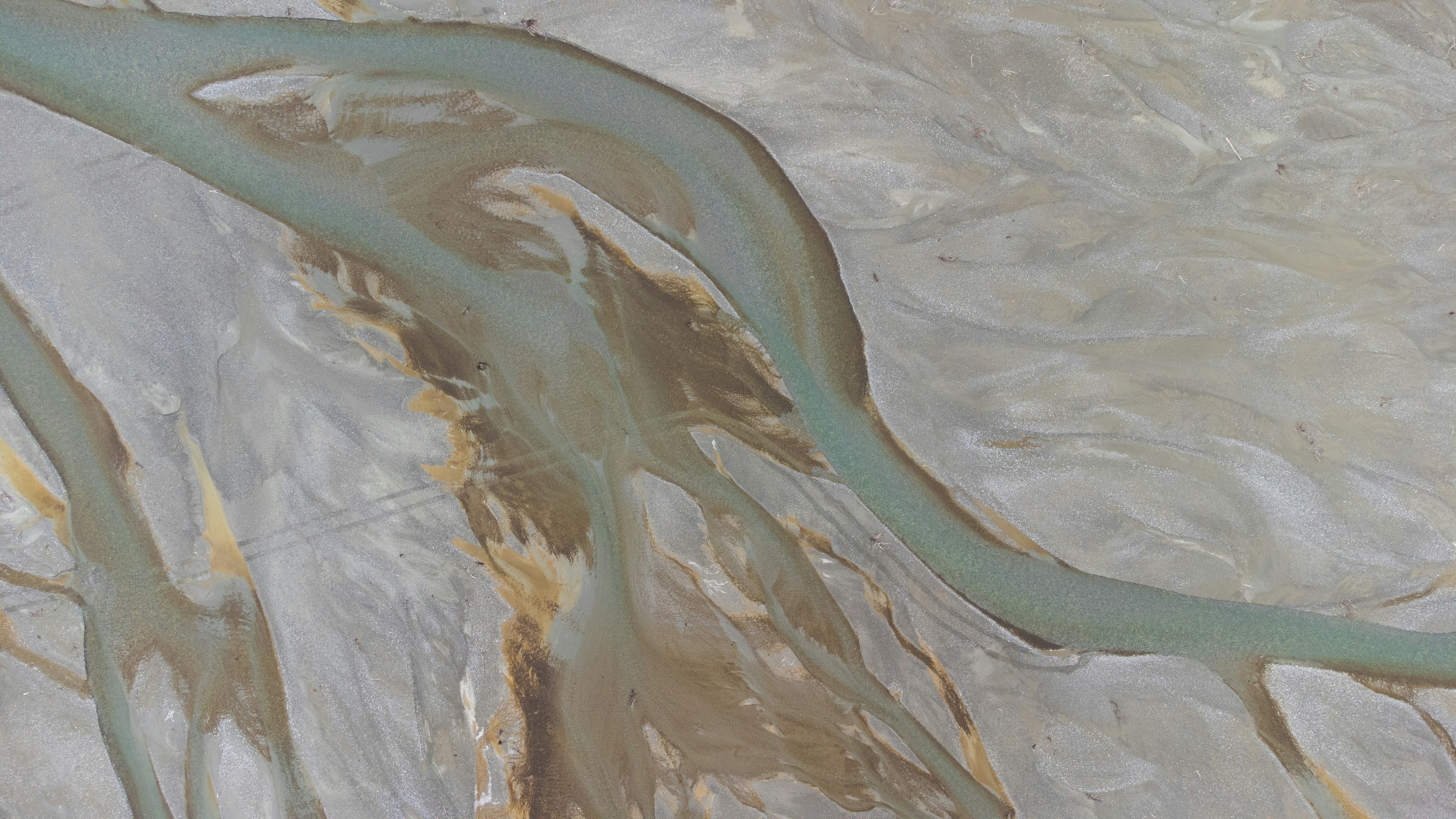 Aerial view of a braided river delta with turquoise water.