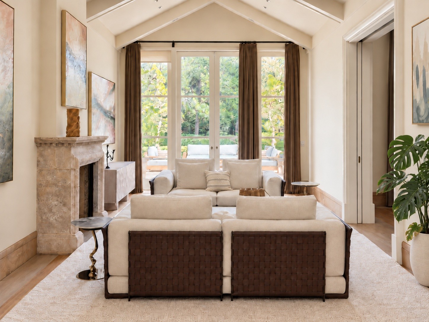 Vaulted living room with tailored ivory cushions, woven leather sofa backs, abstract art and natural green foliage