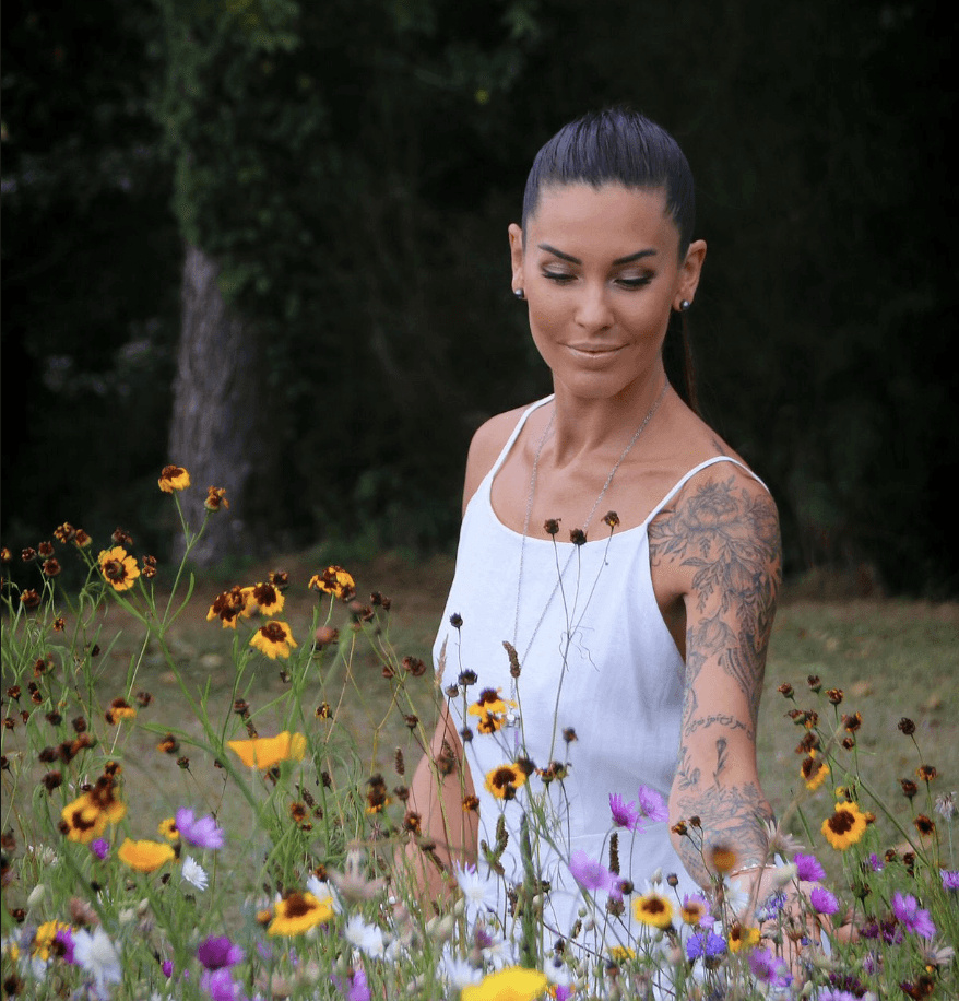 Four friends laughing together outdoors in natural light, dressed in neutral casual outfits.