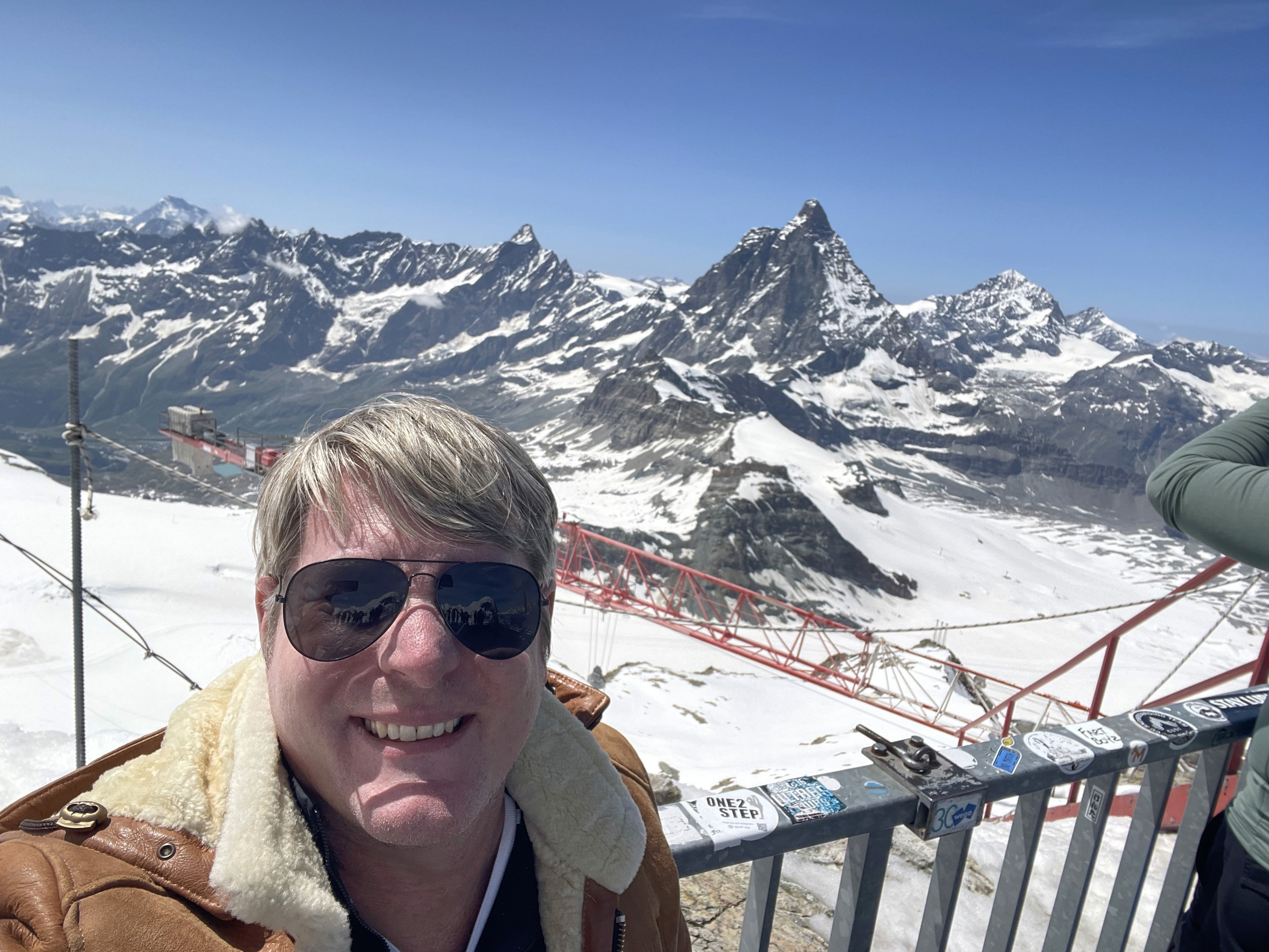 A panoramic view of snow-covered mountain peaks under a clear blue sky.