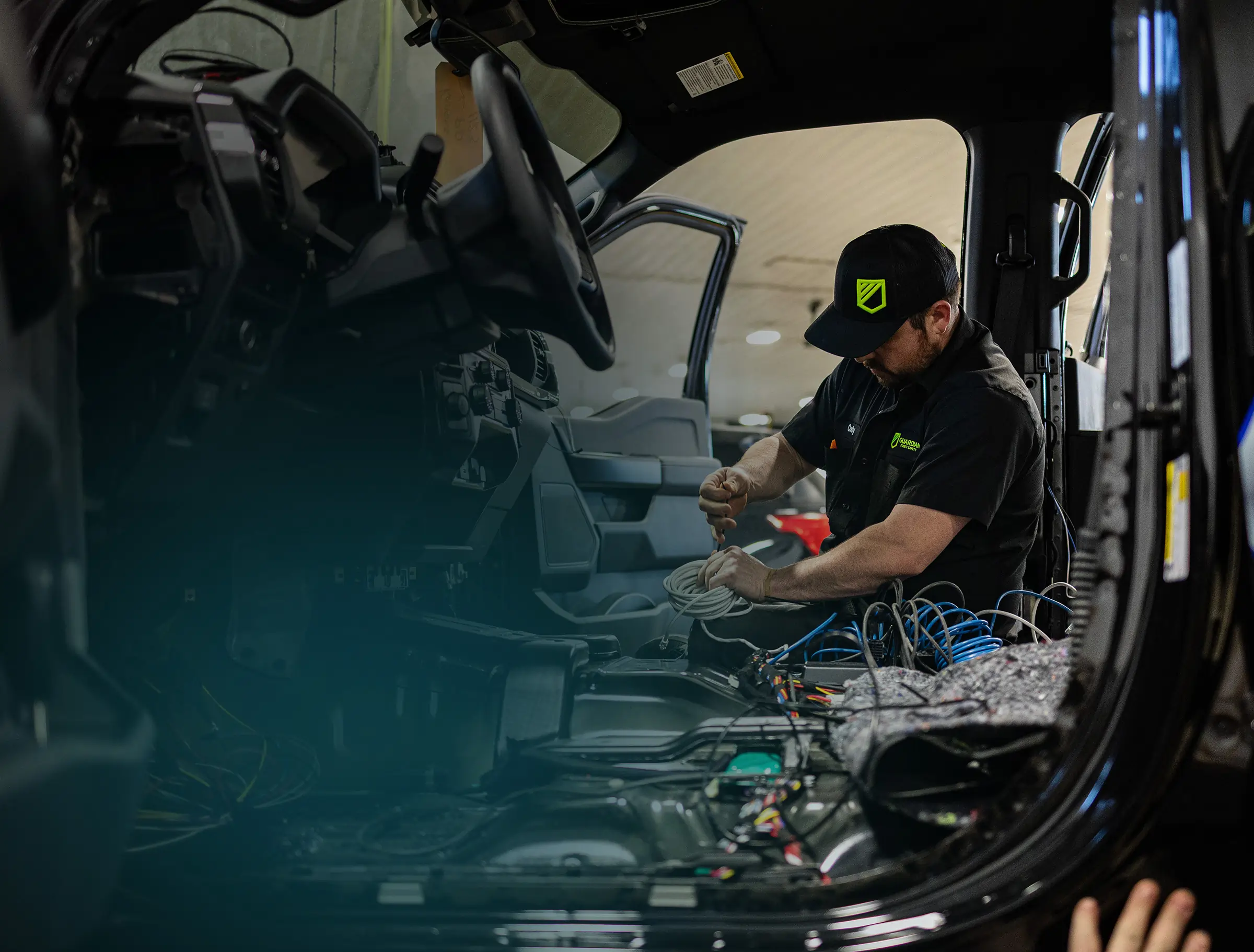 Technician installing wiring inside a vehicle during the upfitting process