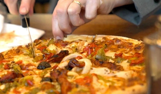 pizza coupé par quelqu'un en gros plan