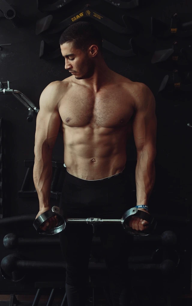 Man resting with eyes closed in a dimly lit gym after physical effort