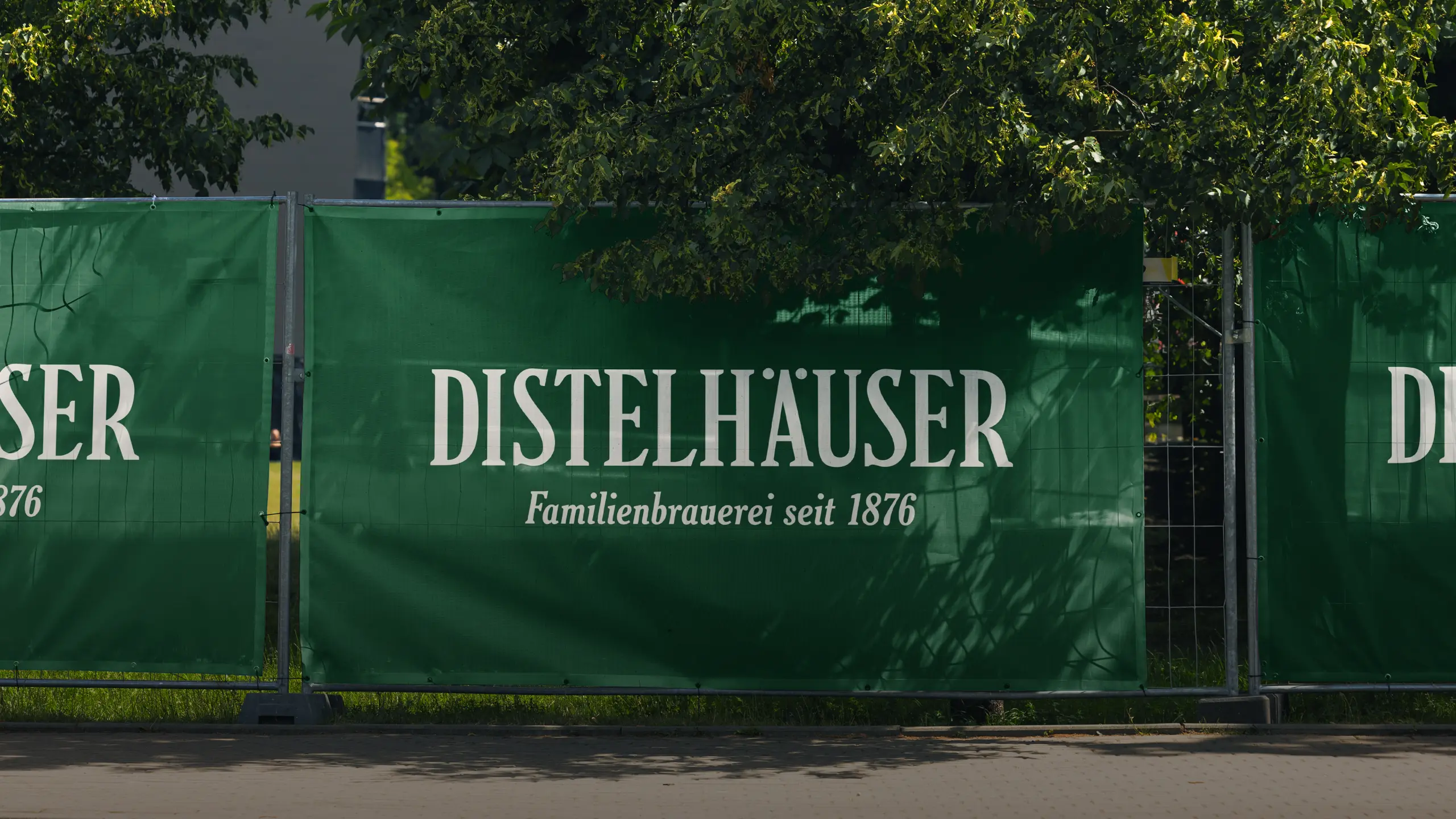 Grüner Bauzaun mit Distelhäuser-Schriftzug und dem Zusatz Familienbrauerei seit 1876