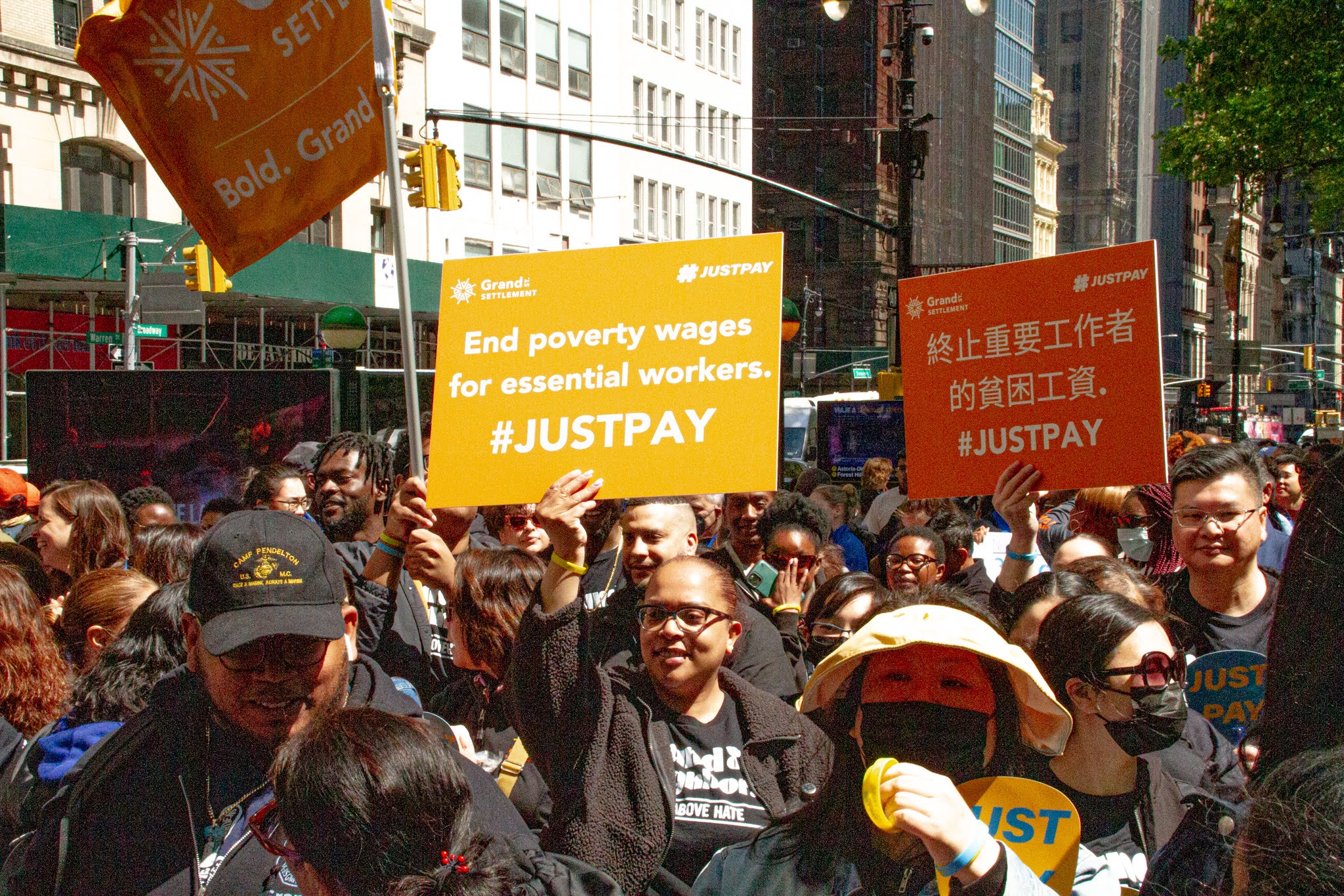 Grand St. Settlement staff stand at a rally with signs advocating for 