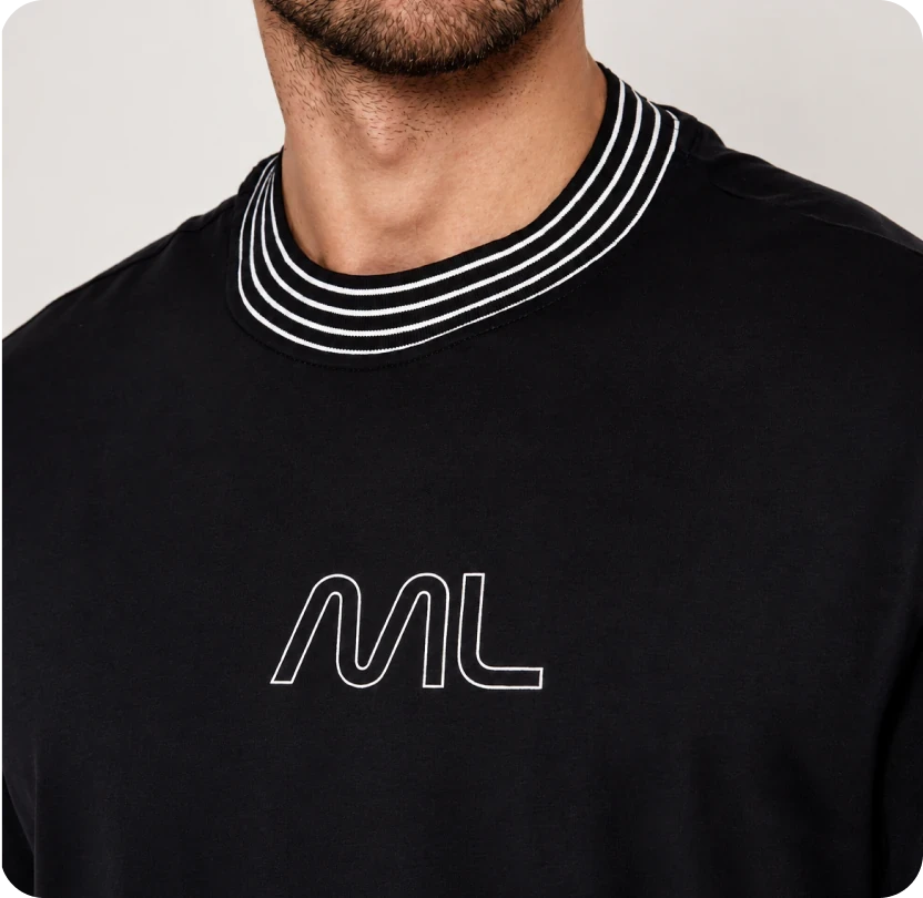 A close-up of a black T-shirt with a striped ribbed collar and the rounded "ML" printed in white outline on the chest.