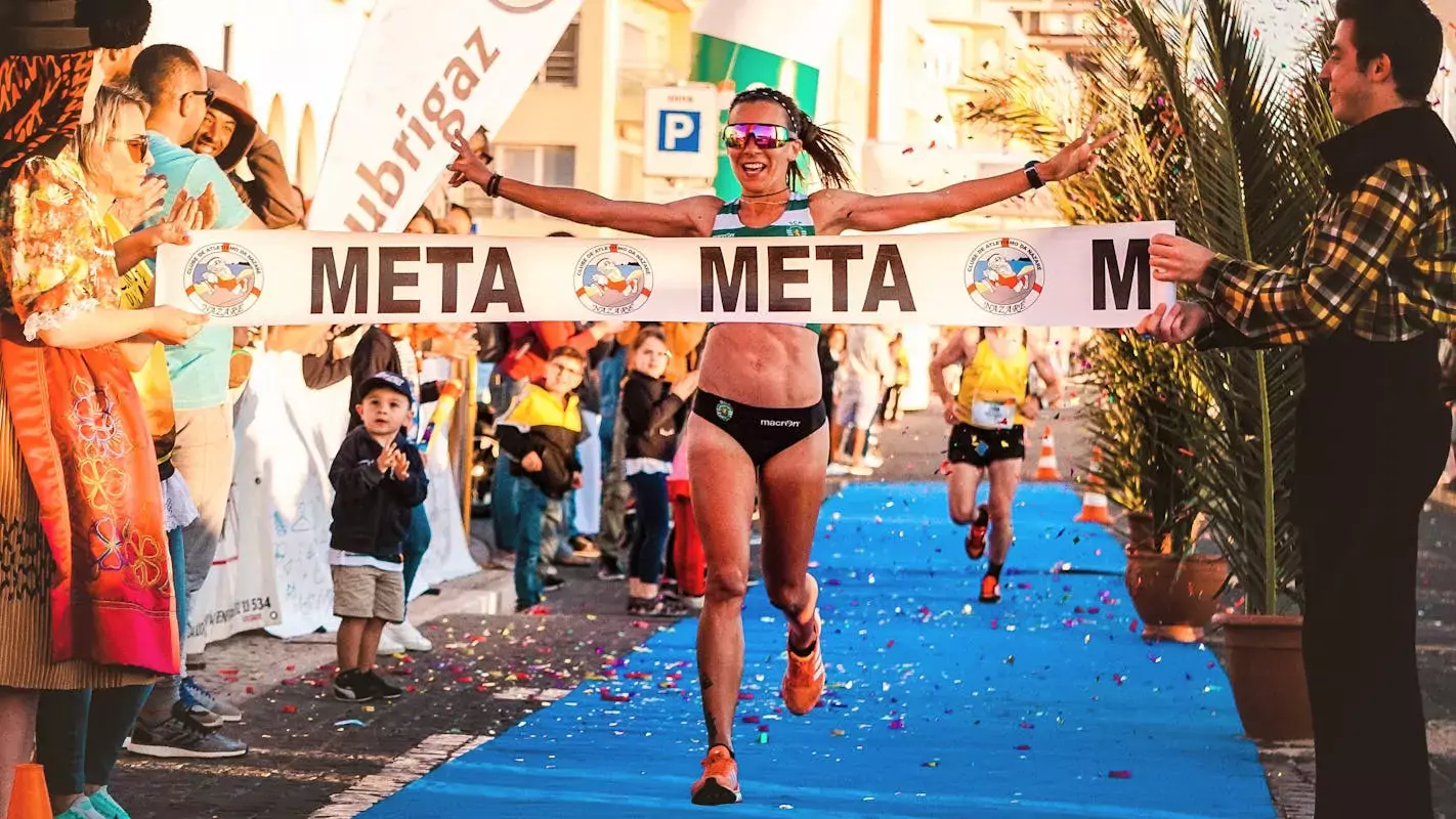 runner coming across the finish line in a celebratory fashion after having won her race