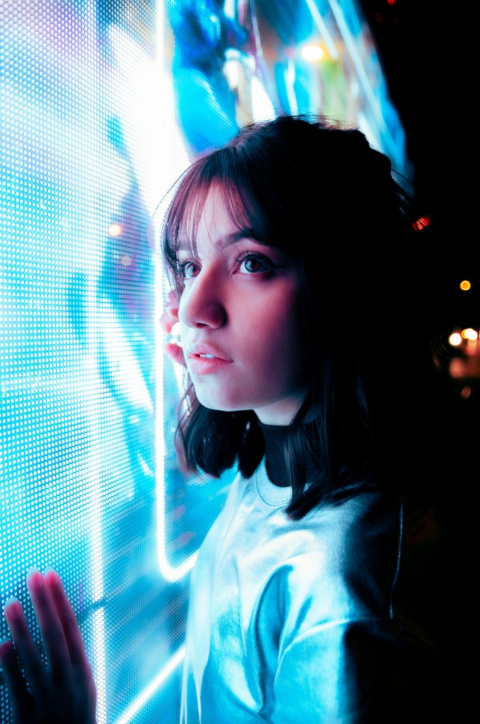 A woman leaning up against a wall of blue lights