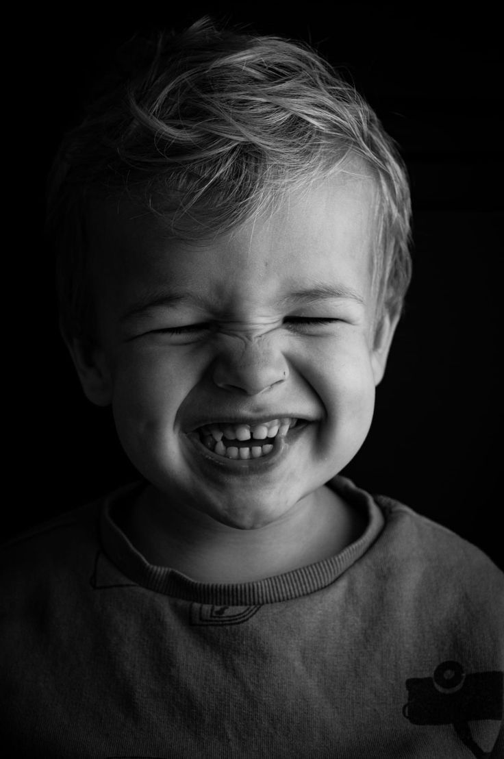 Kleiner Junge mit geschlossenen Augen lacht und zieht Grimassen