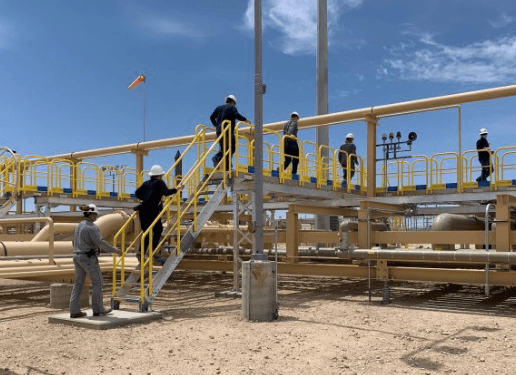 People working on a yellow rail with tools.