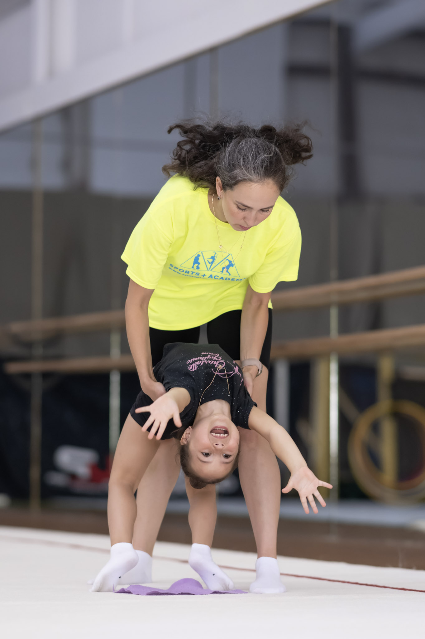 Girl from beginner group being assisted in her bridge or back bend with the assistance of one of our assistant coaches