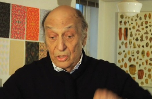 A photo of a man in an art workshop with some pattern designs textures on the walls.