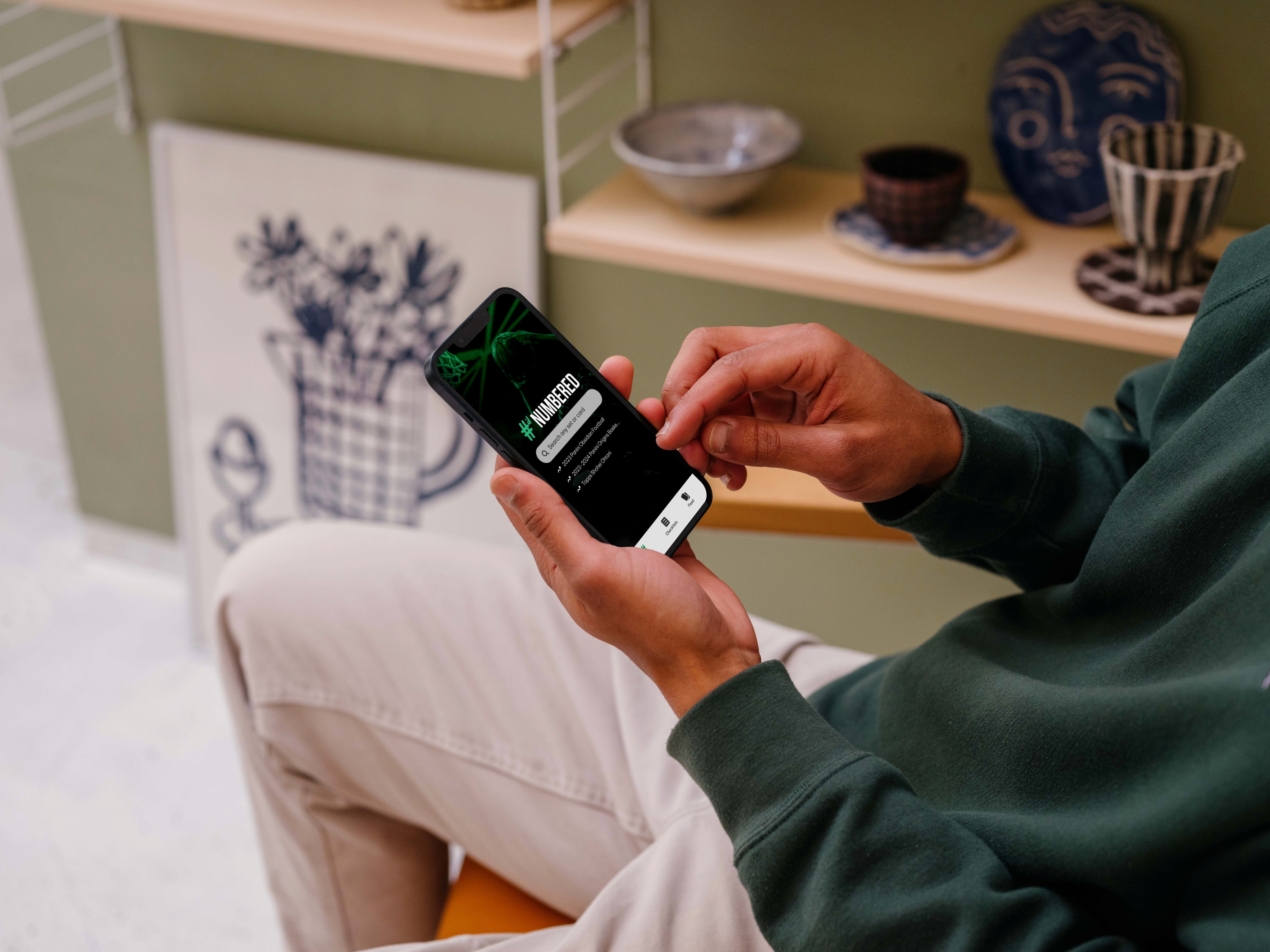 Man holding a smartphone with a baseball card trading app open, showing a digital collection of baseball cards and options for trading in a user-friendly mobile interface.