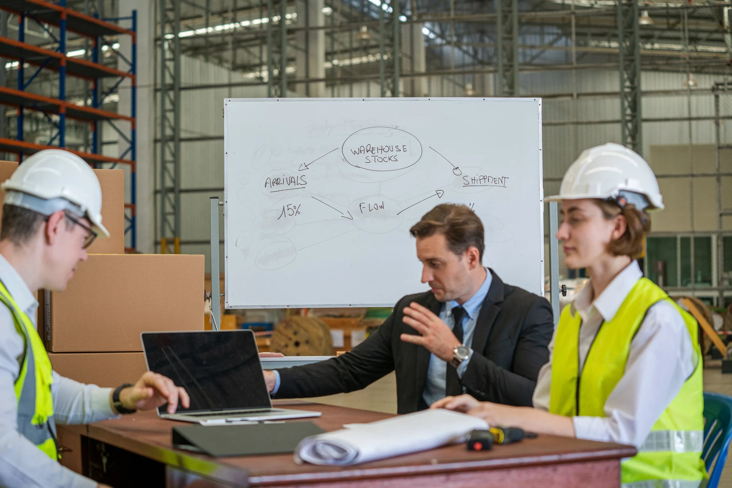 Team meeting around a whiteboard in a plant office, working through a problem together.