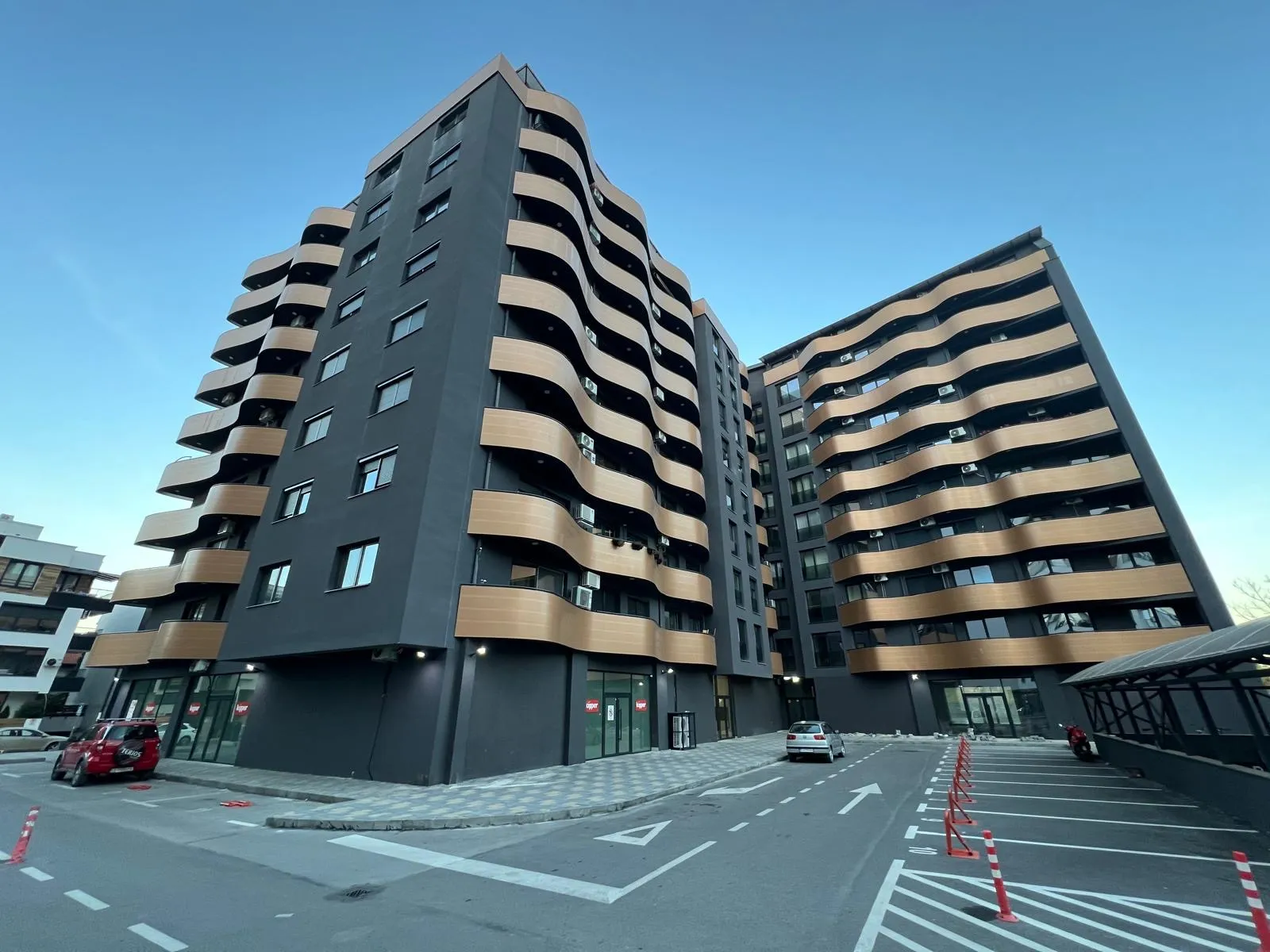Wide view of a contemporary residential building in Skopje with wave-shaped balconies and large window openings. Terraplan Partners provided project supervision.