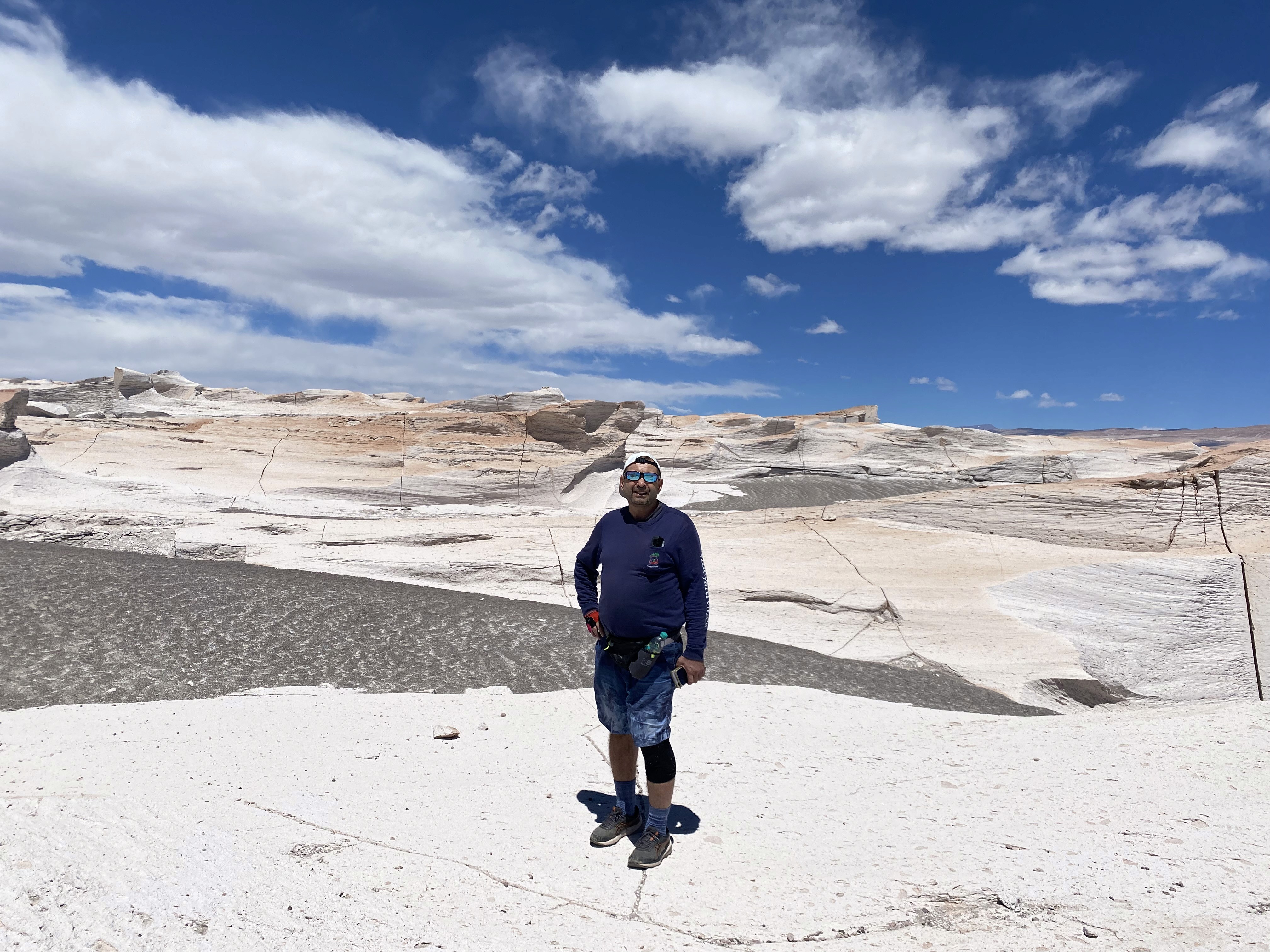 Mujer sentada sobre un tronco frente a una cascada doble en un bosque frondoso de Argentina.