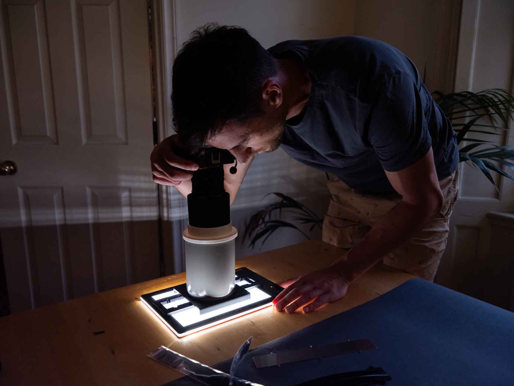 A photographer with his DSLR scanning setup for digitising analogue photographs 