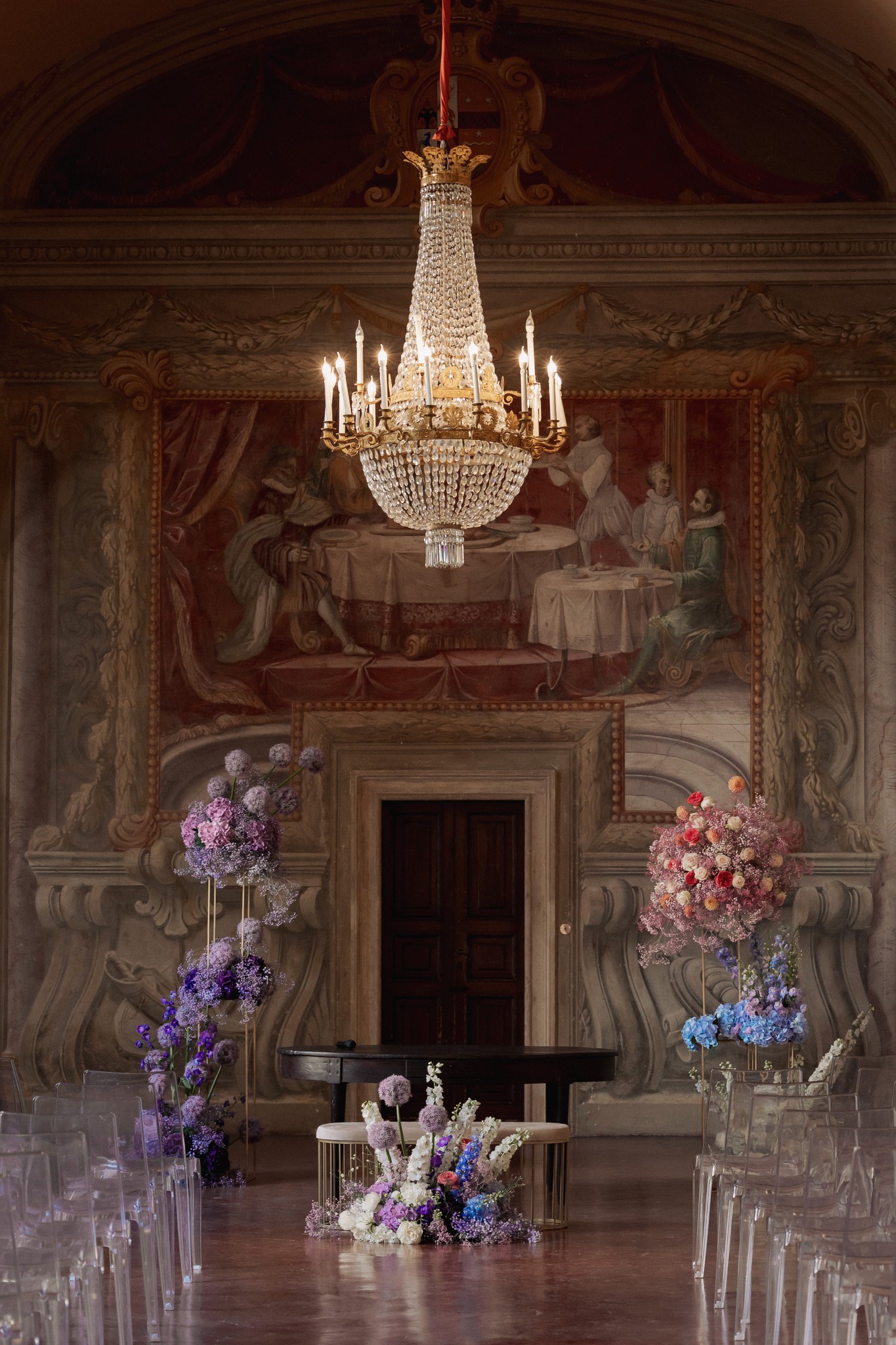 Navata della Rocca di Soragna con fiori viola e rosa, lampadario di cristallo e sedie bianche per la cerimonia