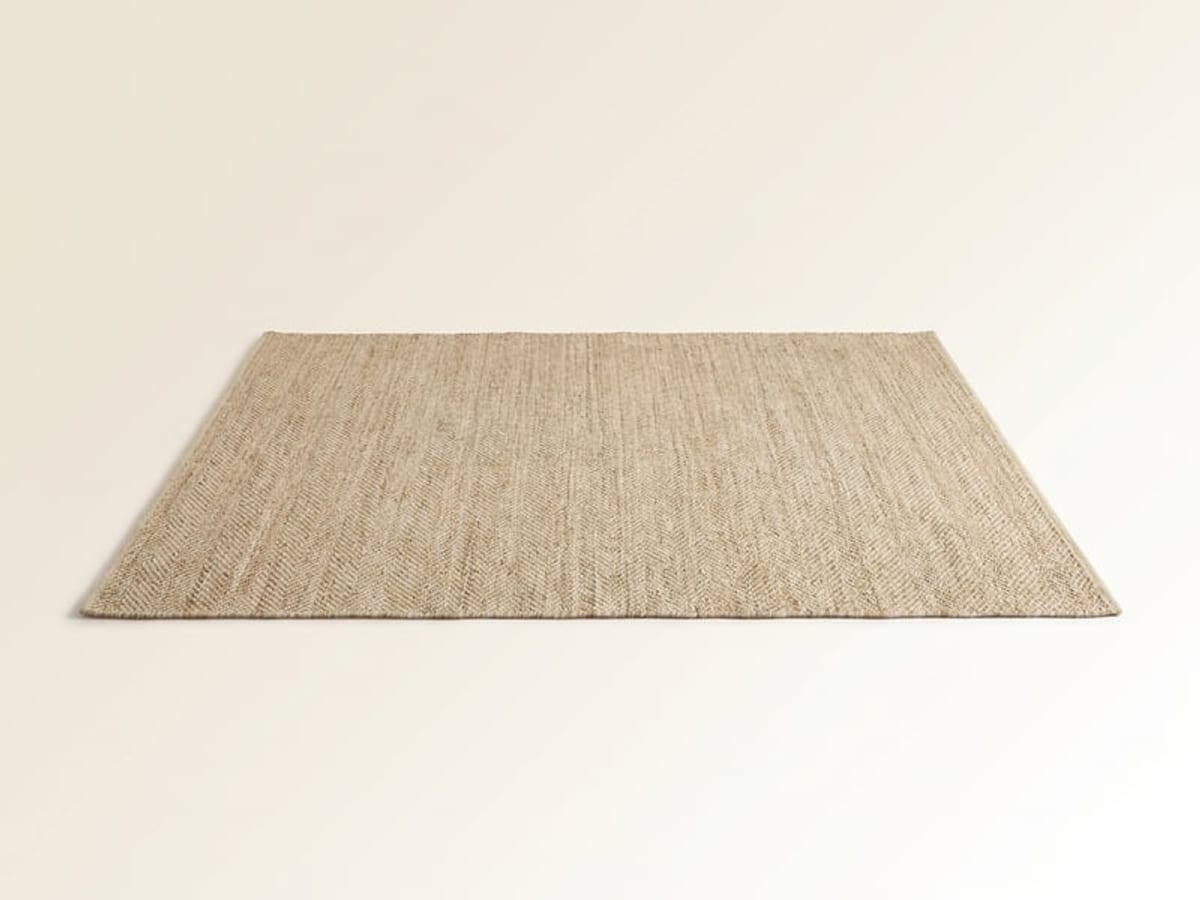 Rechteckiger flach gewebter Teppich aus Jute in Naturfarbe vor hellem Hintergrund