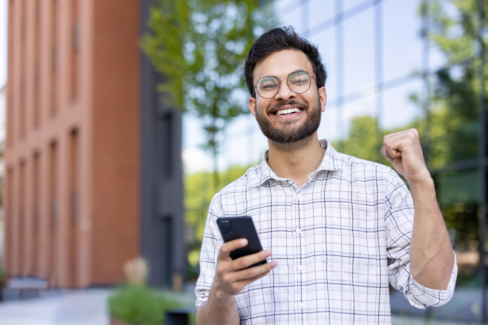 Homem jovem comemorando segurando o celular