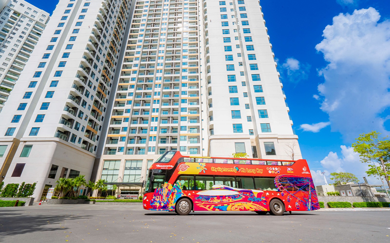 红色双层巴士停靠在高楼附近，为下龙湾随上随下游提供服务。