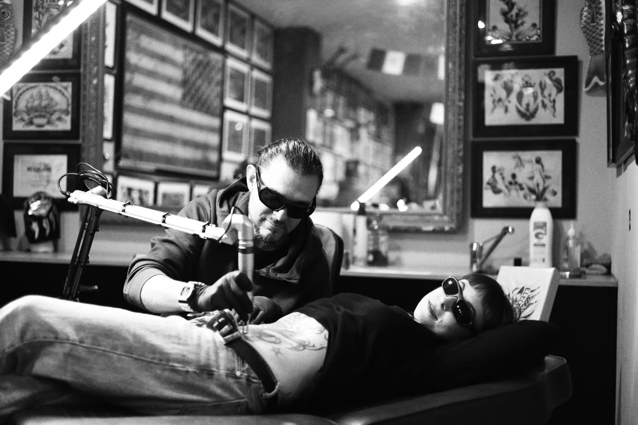 Tatuador trabajando sobre el brazo de un cliente en un estudio de tatuajes