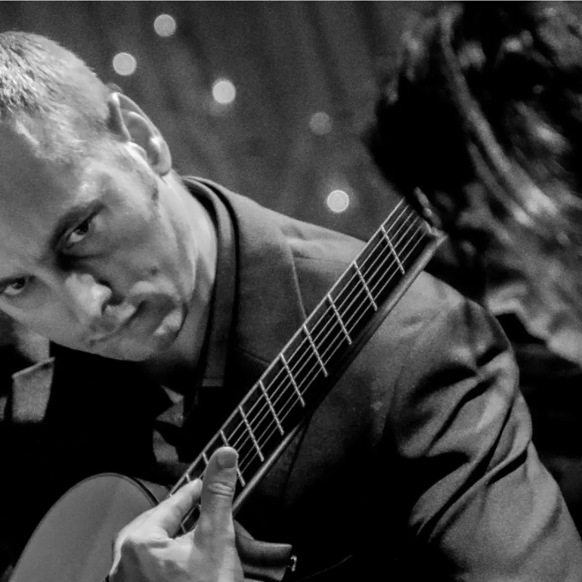 An experienced music instructor is guiding a student in learning how to play the guitar.