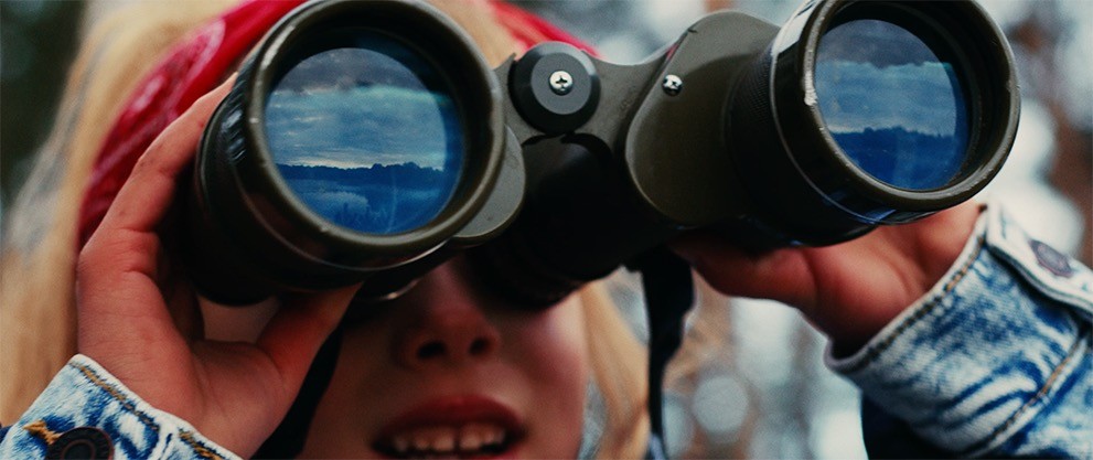 Young girl looking through big binoculars