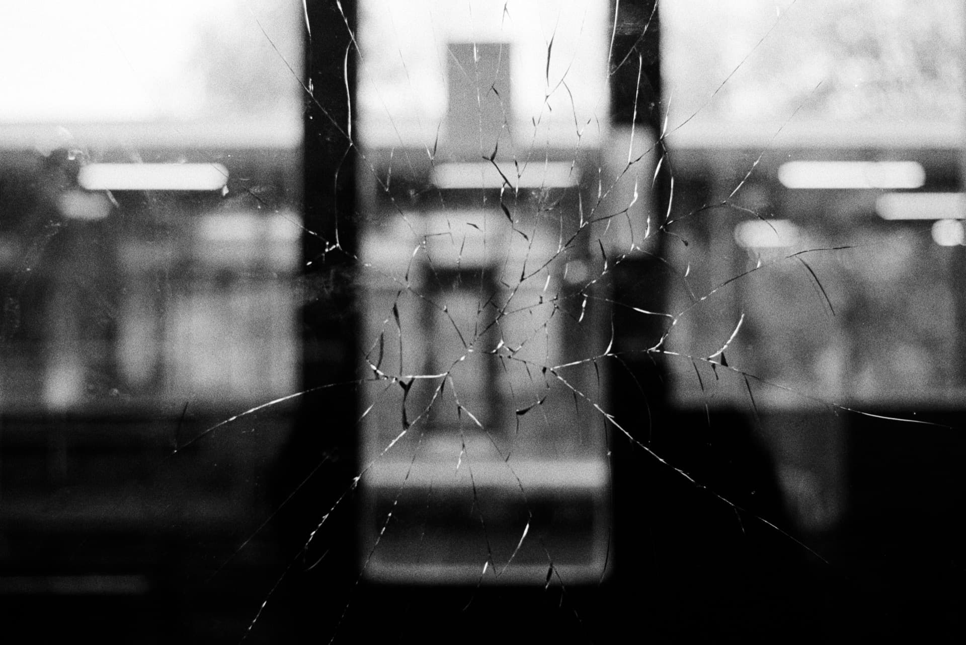 Shattered glass door with radial cracks revealing waiting room interior with seating