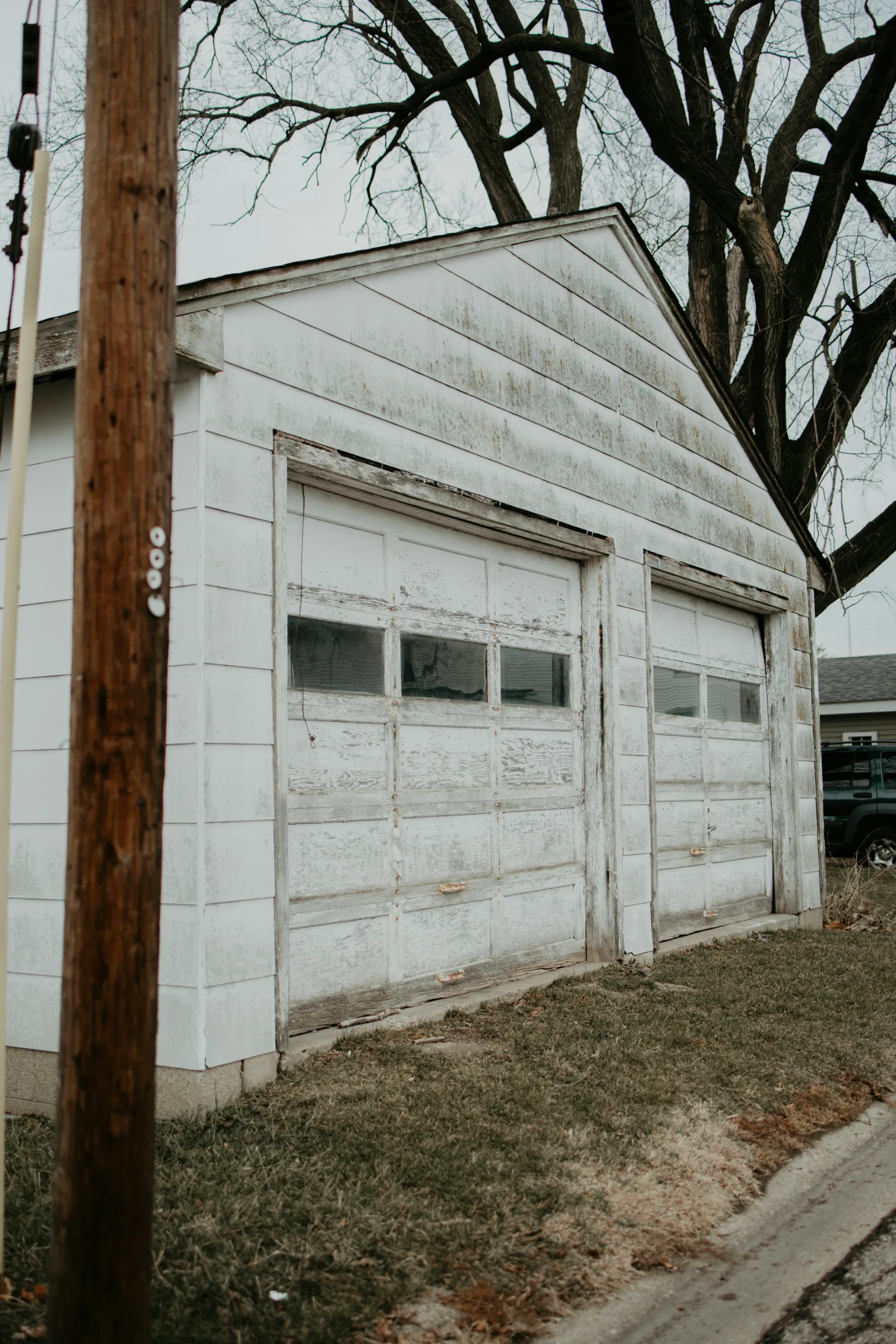 Old white garage with worn doors. Needs garage door repair or new garage door in Rio Rancho.