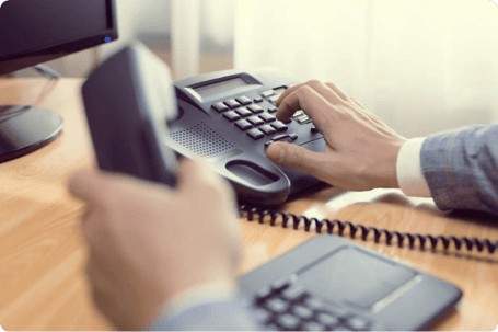 Main utilisant un téléphone, symbolisant le service de prospection téléphonique de l’entreprise.