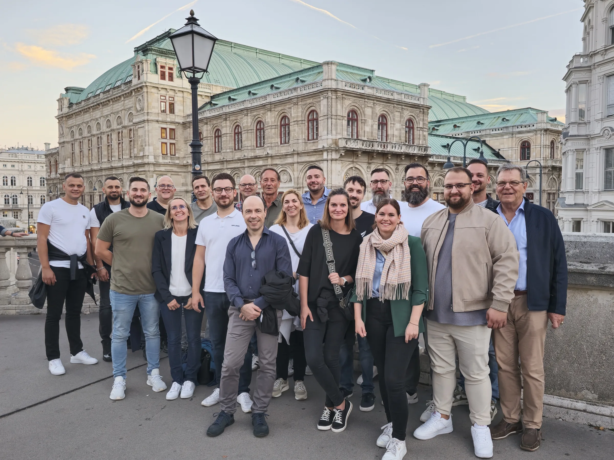 Grosses Gruppenfoto des trimaster-Teams vor der Wiener Staatsoper im Abendlicht