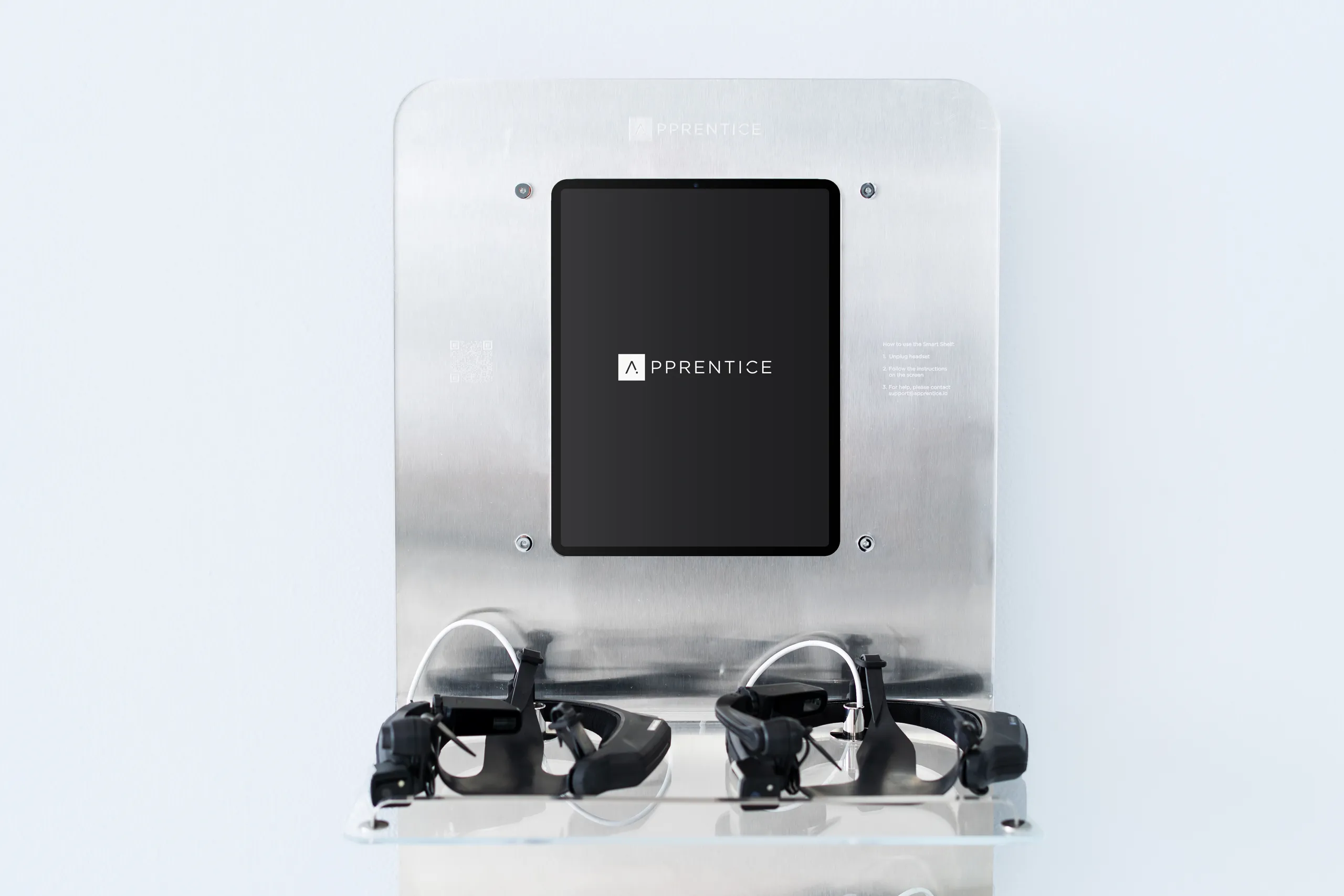 Wall-mounted Apprentice Tandem Hub with central display and multiple wearable headsets docked below