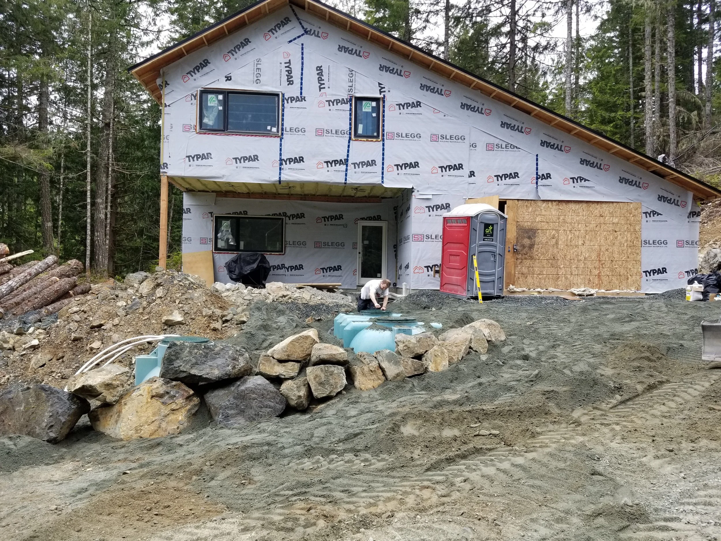 Modern two-story home with large glass windows, warmly lit interiors, and a balcony. Surrounded by trees and a manicured lawn at dusk. Cozy ambiance.