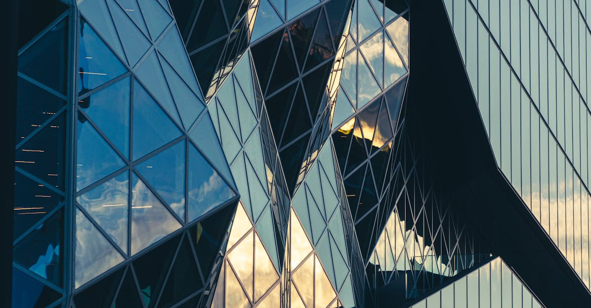 Geometric glass facade reflecting the sky, showcasing modern architectural design.