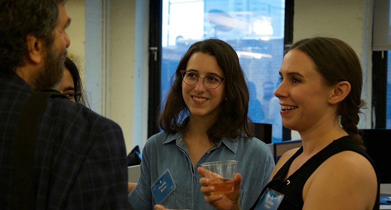 A photo of a group of people sitting in an office room and talking.