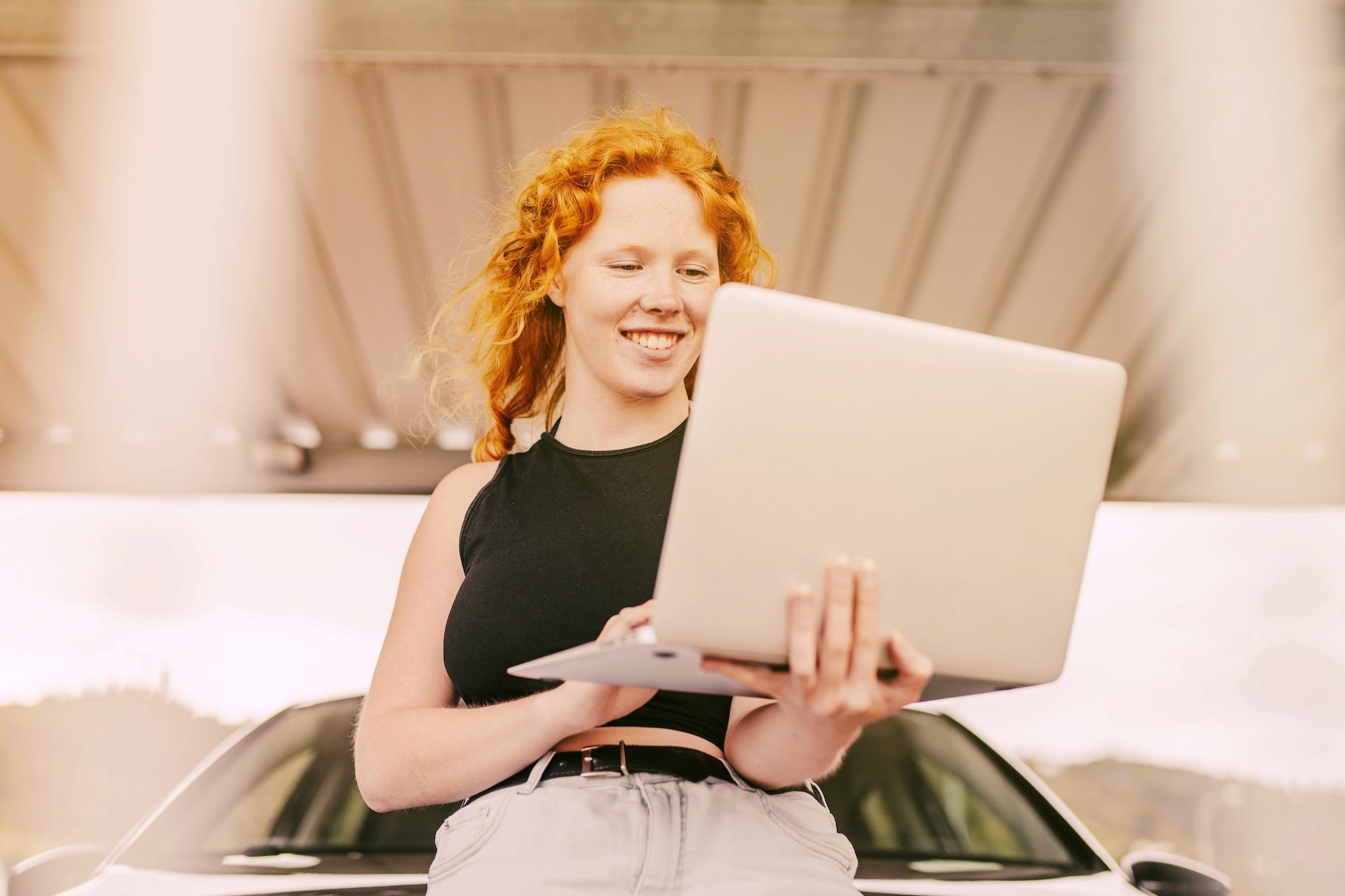 Smiling red-haired woman holding a laptop, looking approachable and friendly
