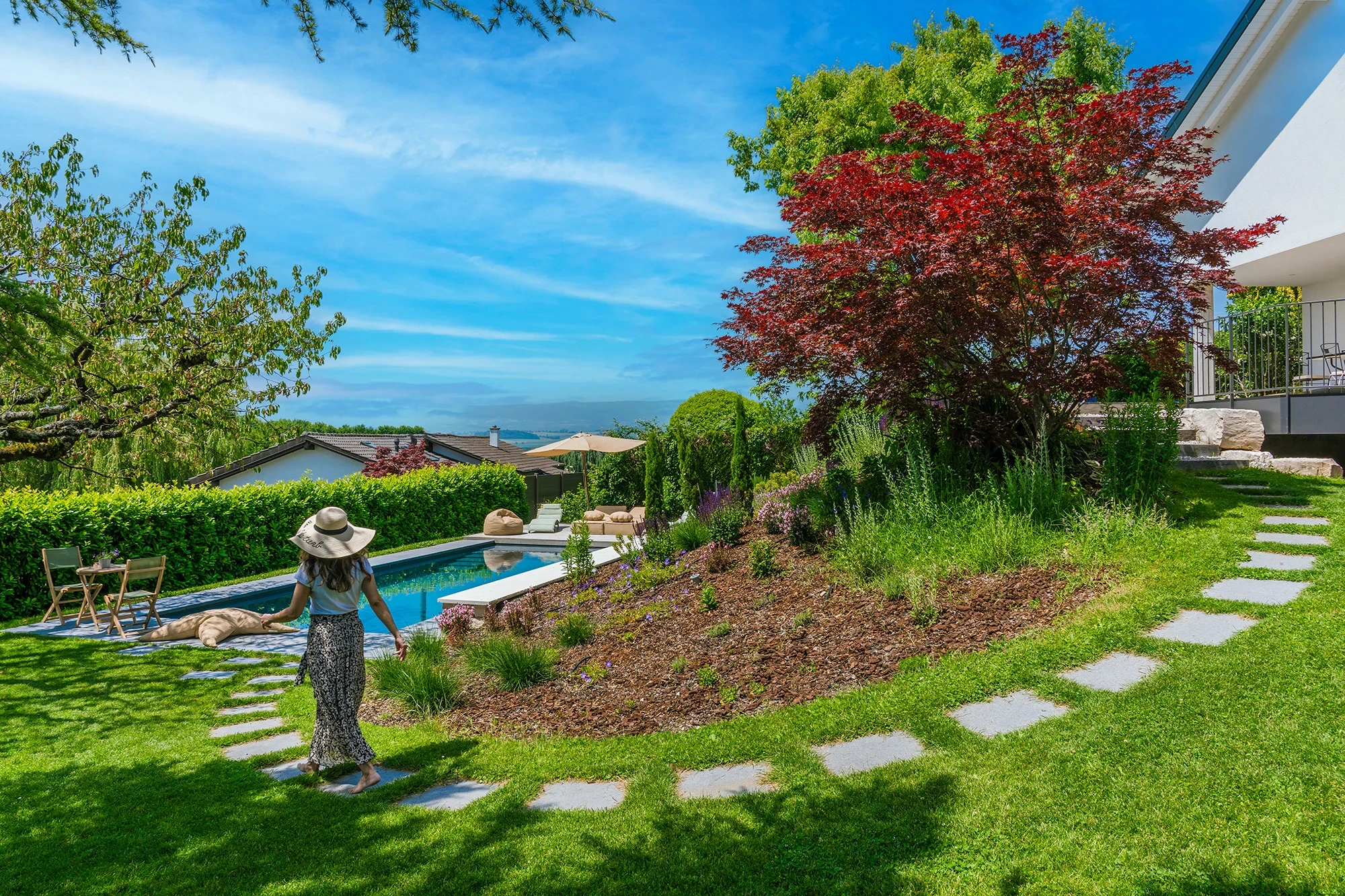 Jardin paysager avec bassin et arbre aux feuilles rouges