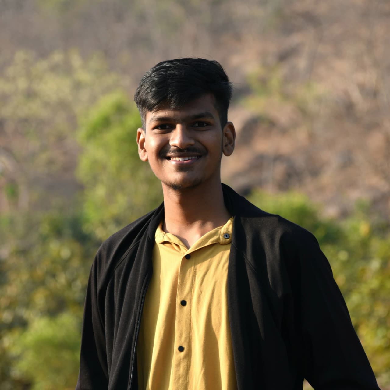 a man wearing glasses and a blazer with a lighting that casts a soft shadow on the wall behind him