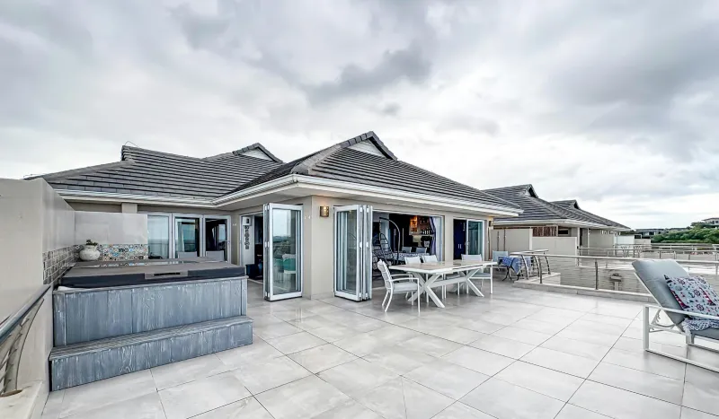 Modern terrace with outdoor seating and a barbecue area, under a cloudy sky.