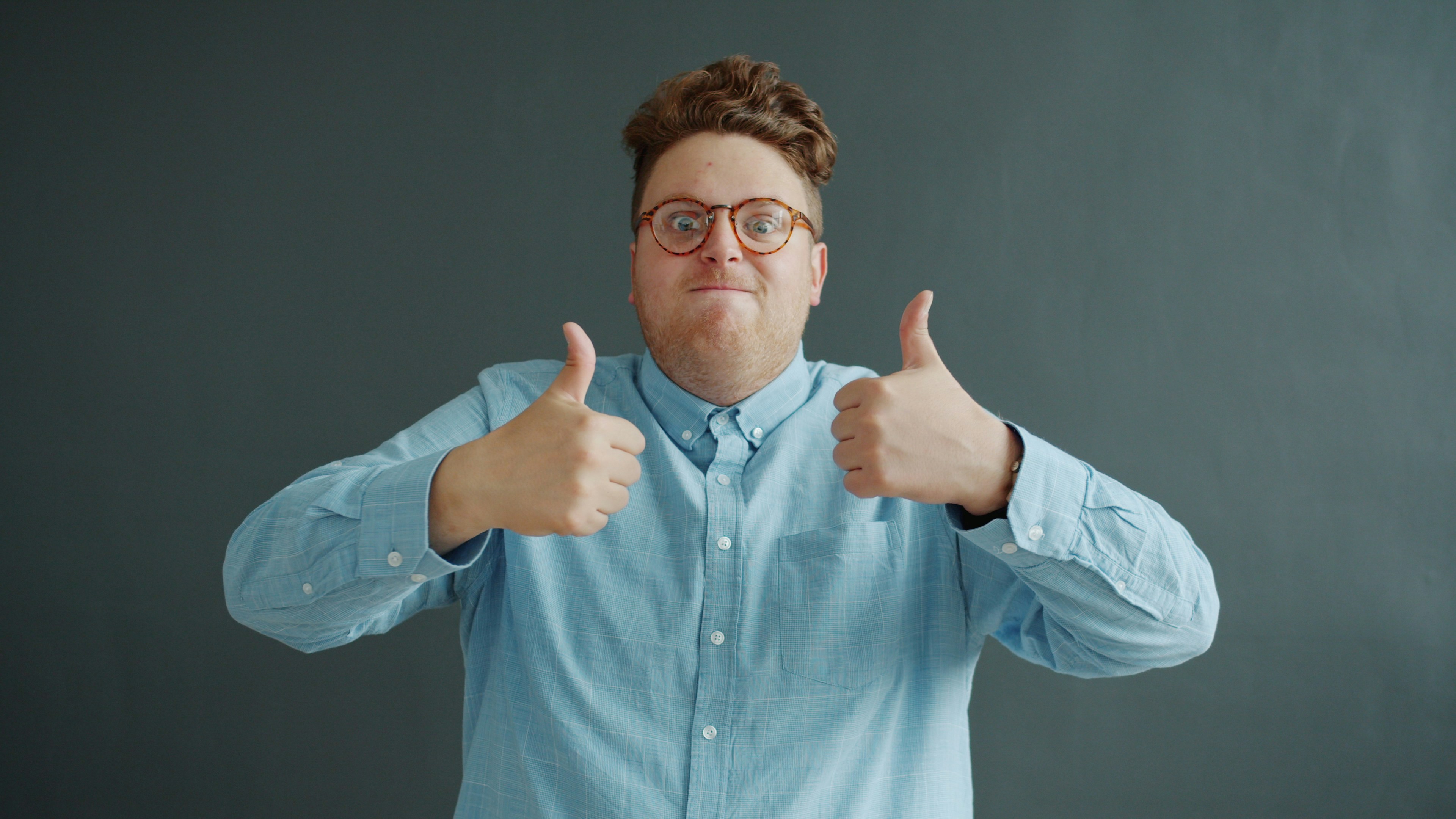 Man with glasses gives two thumbs up.